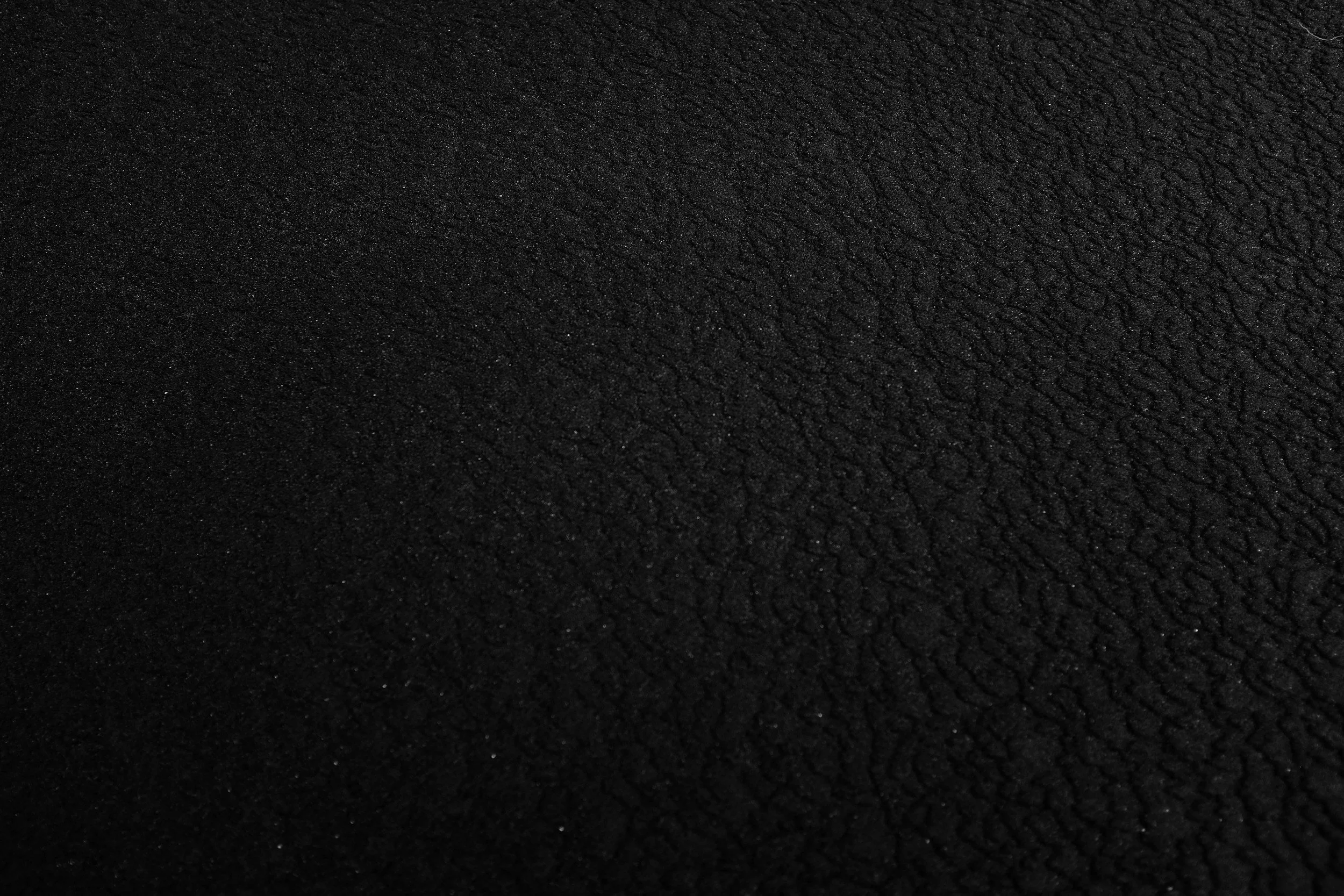 Close-up of a black textured surface, possibly a fabric or material with a grainy pattern.