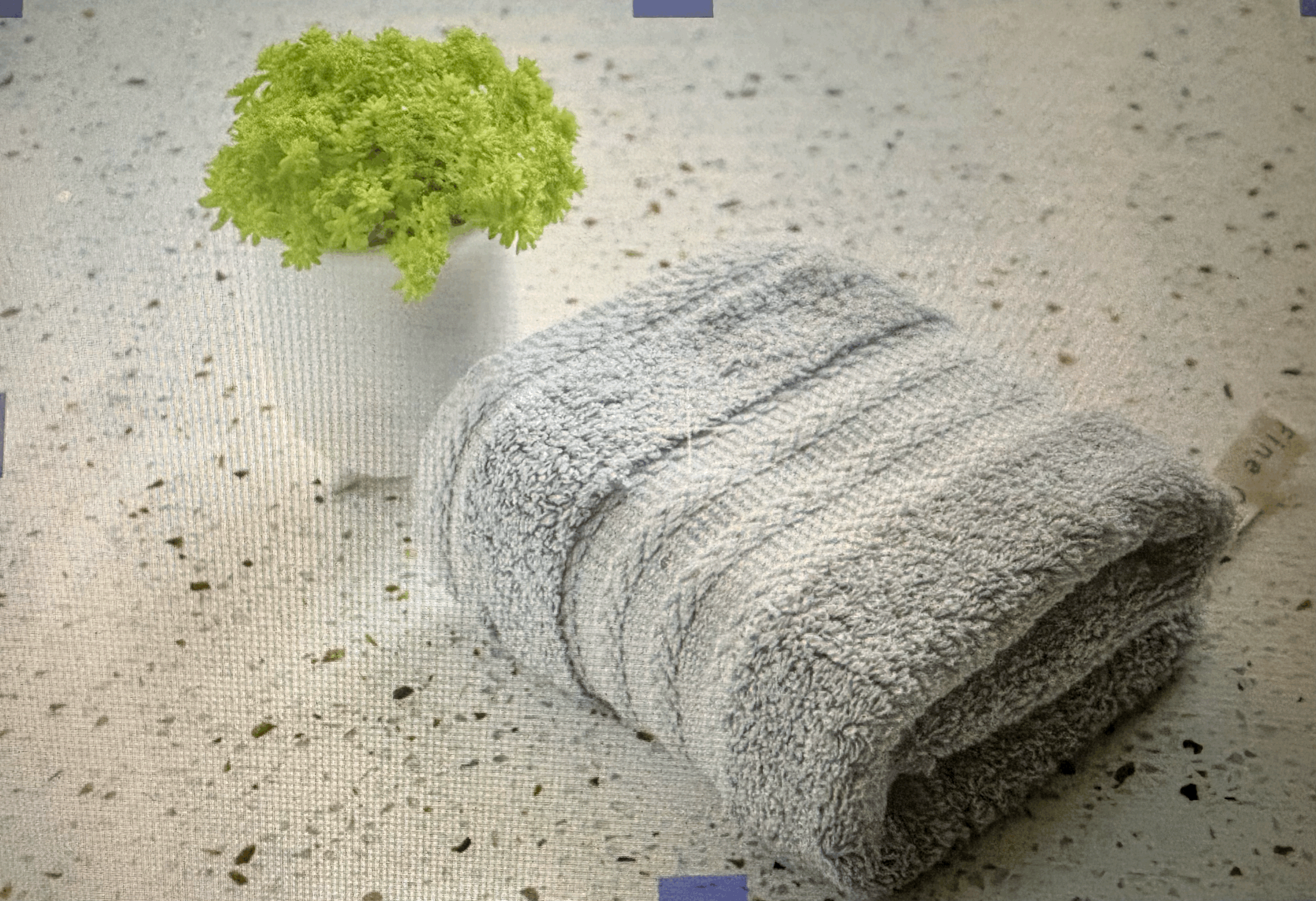Close-up of a rolled towel, some loose green herbs, and a small pile of white powder on a speckled gray surface.