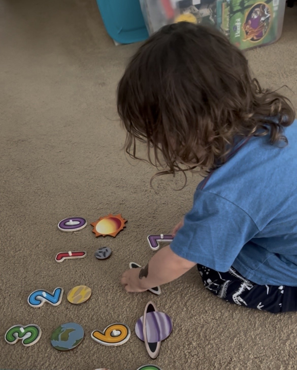 Child sitting beside carefully lined-up number toys, inspiring the beginning of LearnNova Kids
