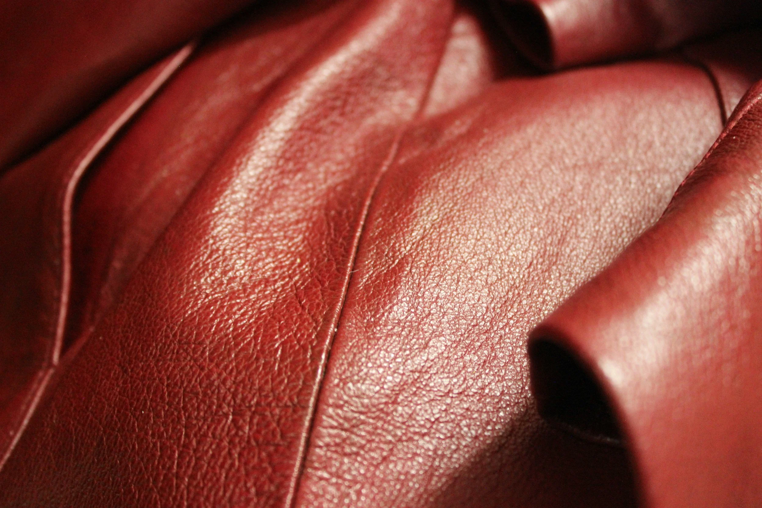 Close-up of red leather material, showing texture and stitching.