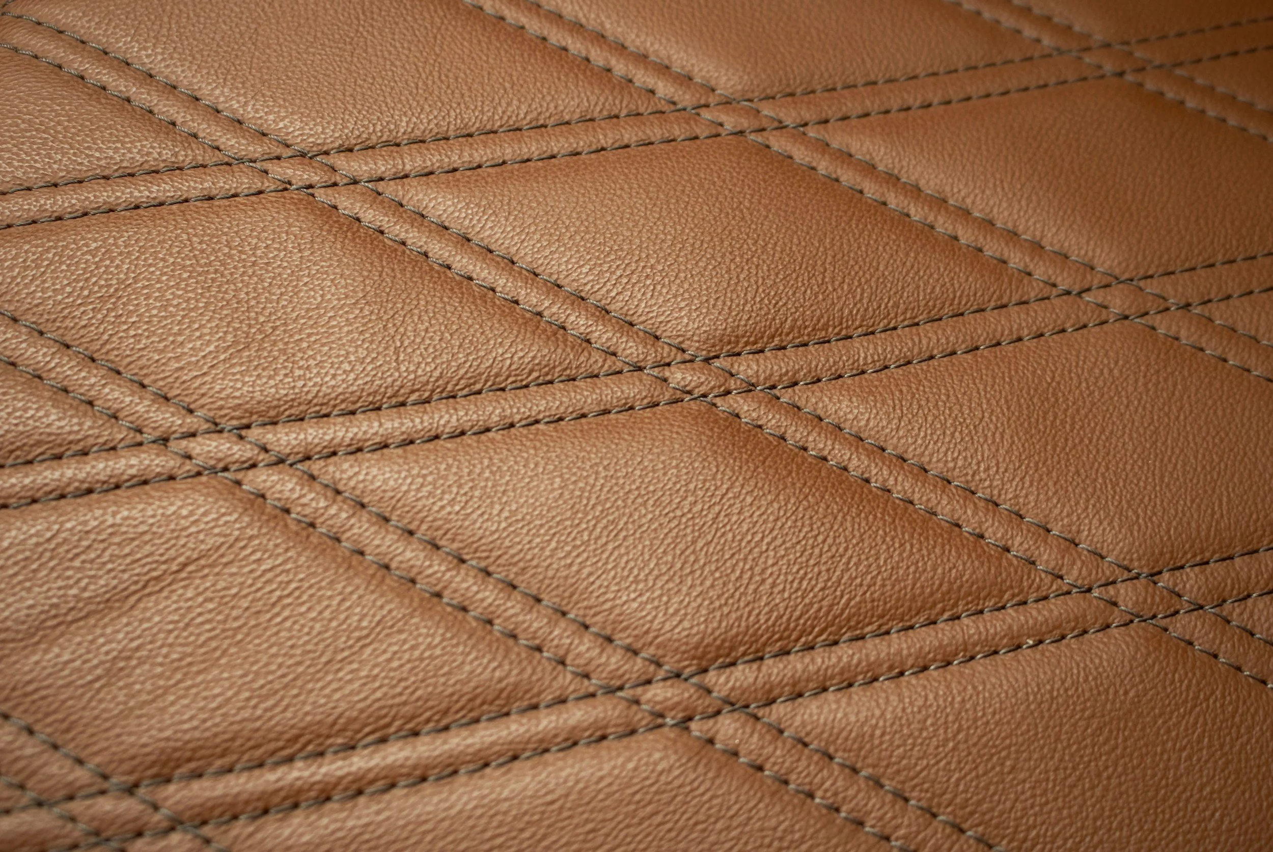 Close-up of brown leather upholstery with detailed stitching in a diamond pattern.