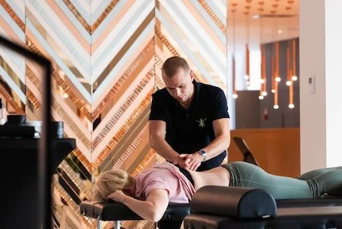 Fizjoterapeuta wykonujący terapię manualną i masaż biurowy dla pracownika firmy.
