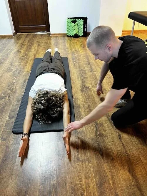 Fizjoterapeuta instruuje pracownika podczas ćwiczeń korygujących postawę w ramach programu ergonomii pracy.