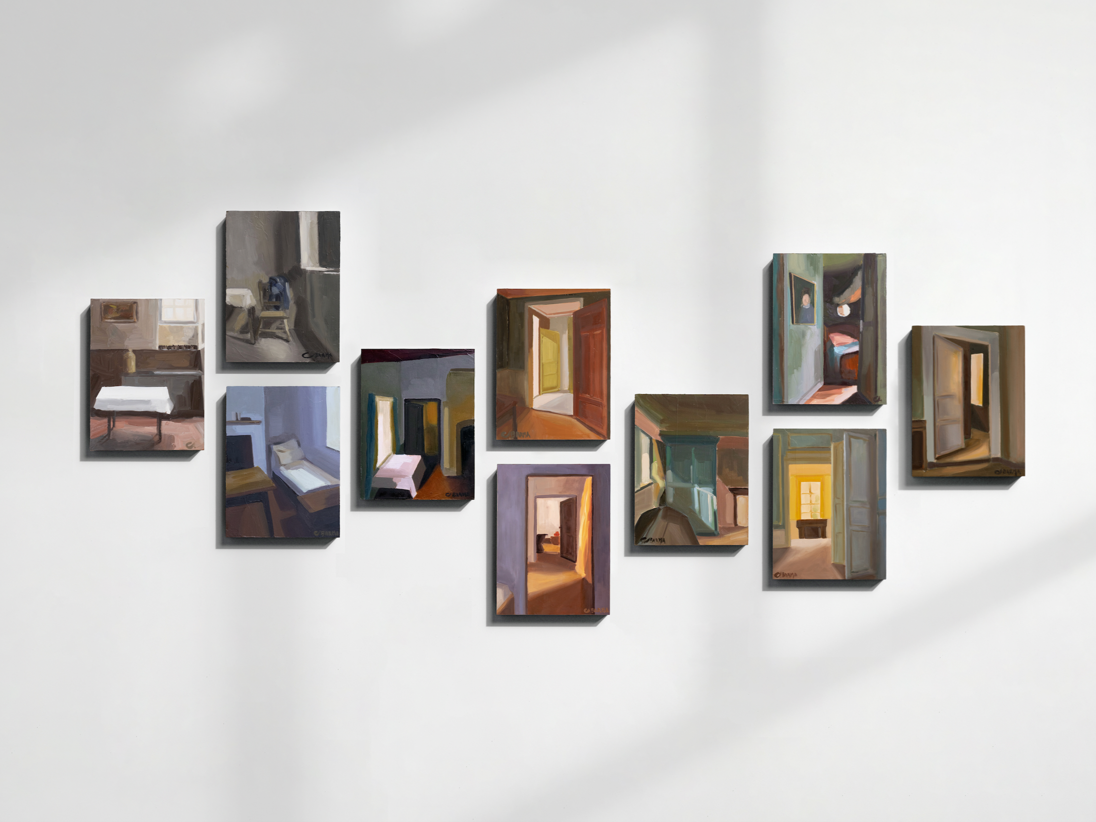 Une série de petites peintures sur toile représentant des portes et des scènes d'intérieur, accrochées en rangée sur un mur blanc dans une galerie d'art.