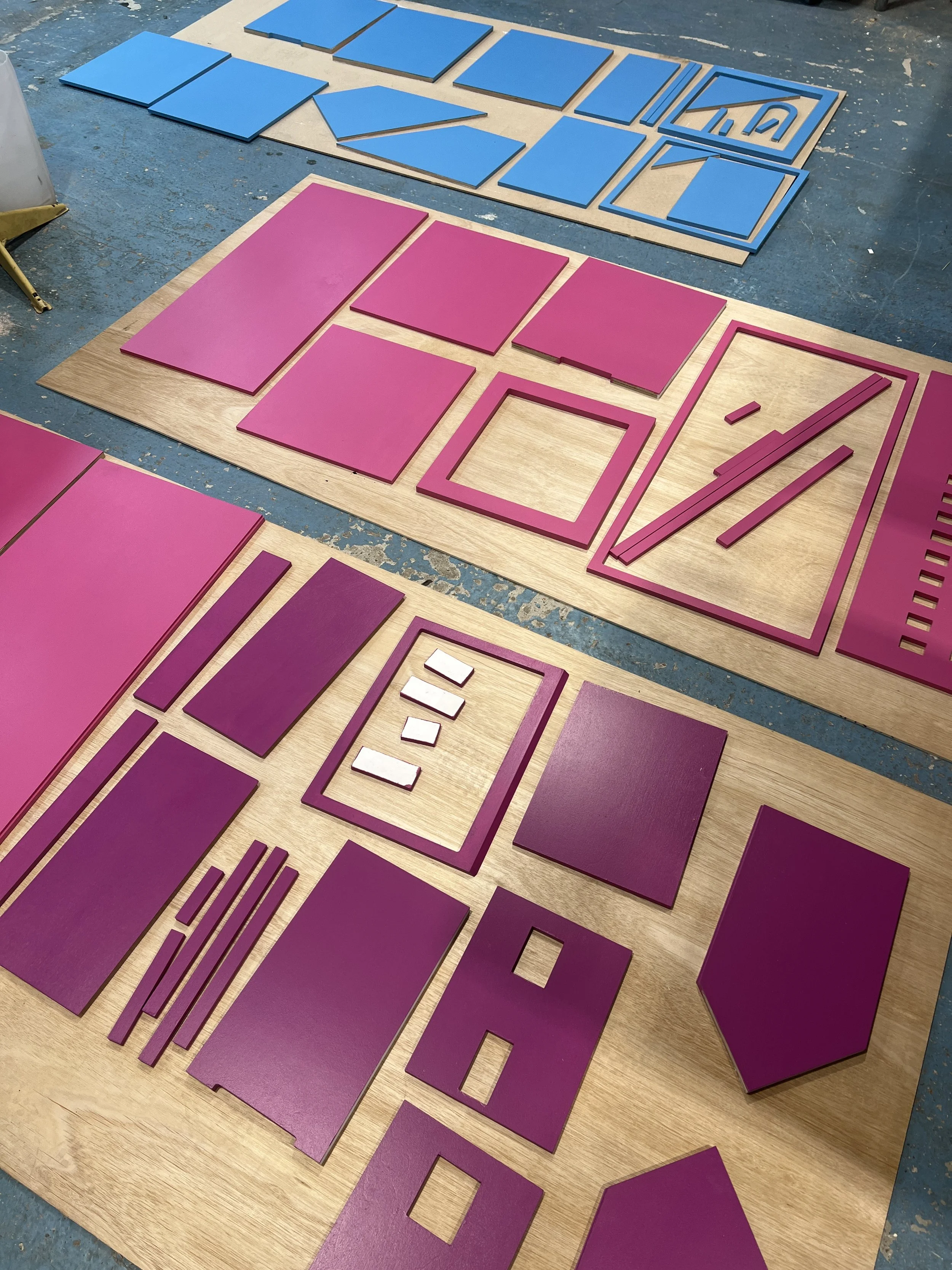 Various purple and blue foam pieces and cutouts arranged on wooden boards, likely for a construction or craft project.