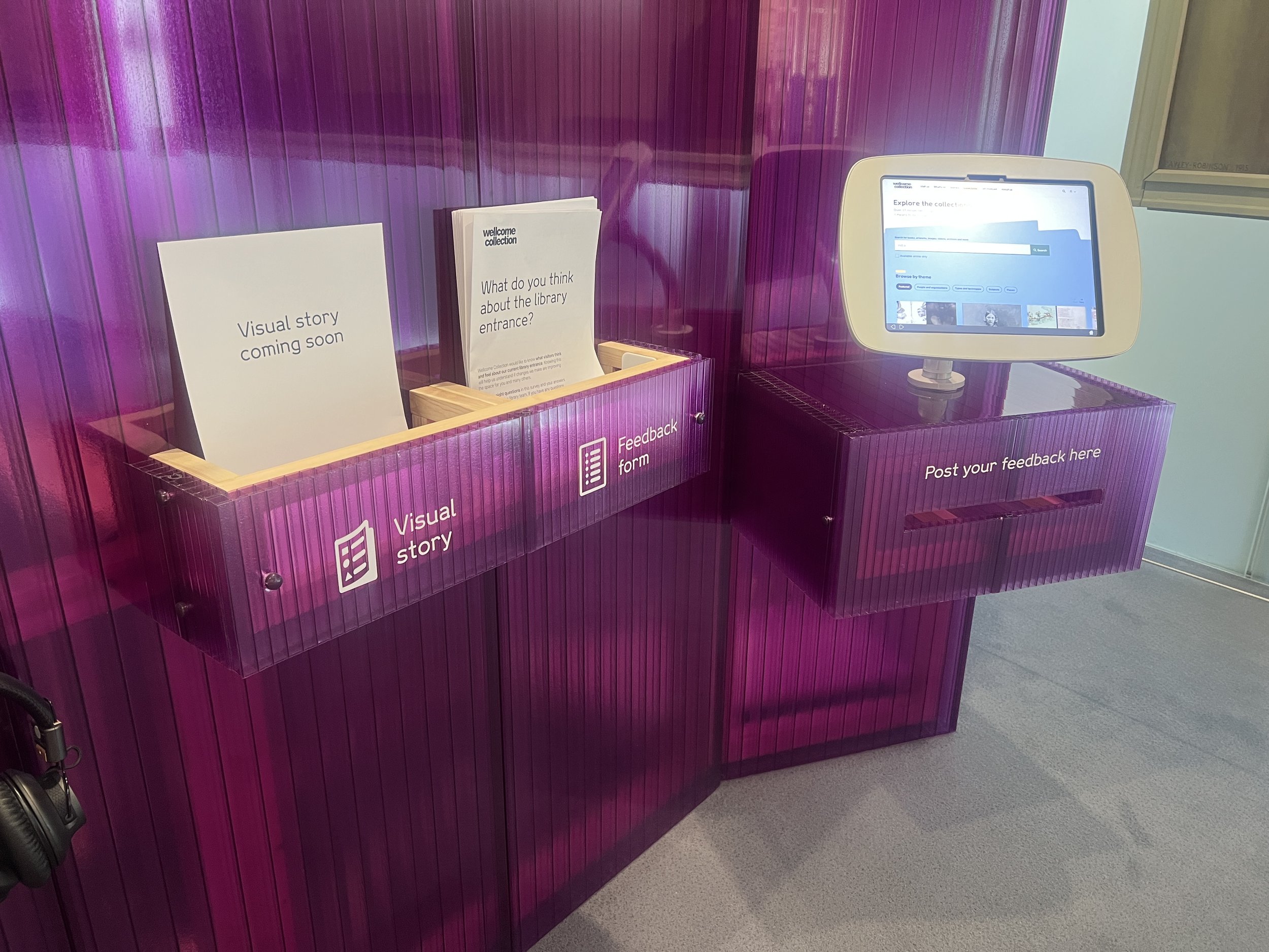 Purple library feedback station with pamphlets and digital screen for collecting feedback.