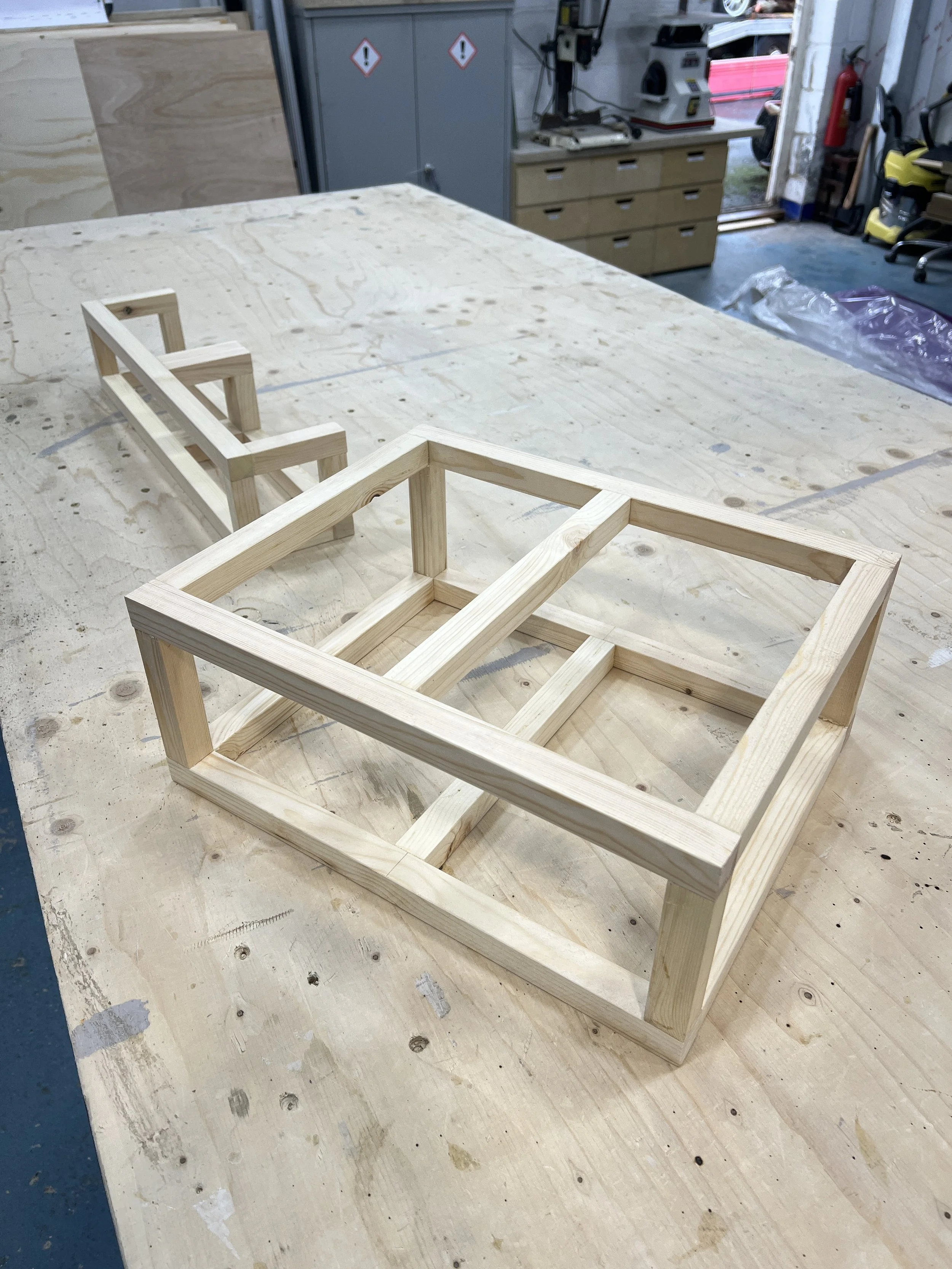 Unfinished wooden picture frames on a workbench in a woodworking workshop.