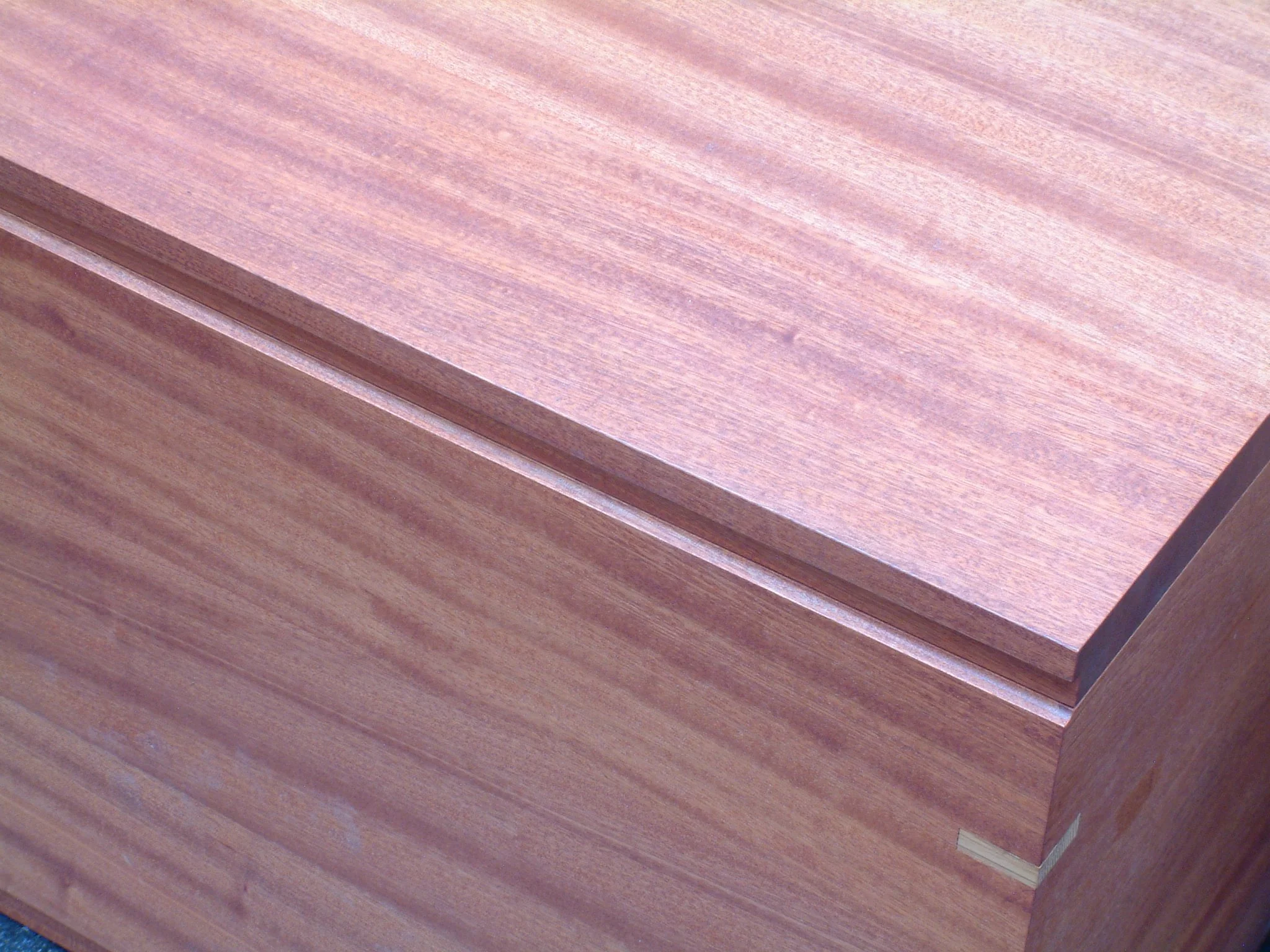 Close-up of a wooden surface, likely a piece of furniture or a wooden box, showcasing the wood grain and texture.