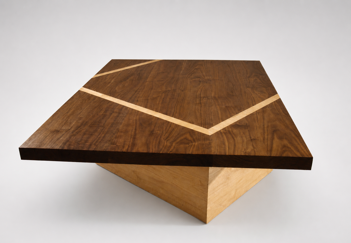 A rectangular wooden table with a geometric design on top, combining dark and light wood with diagonal inlays.