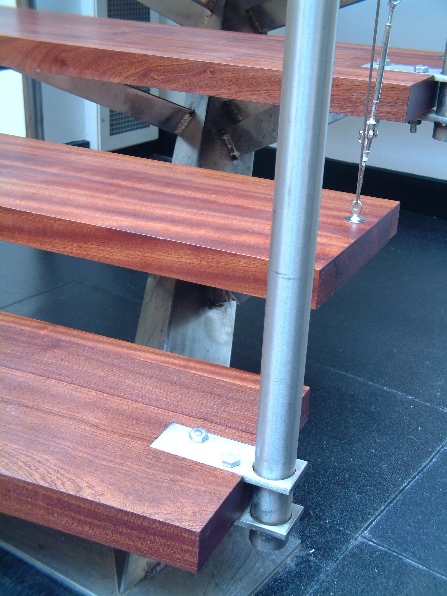Close-up of a wooden bench with metal support and hardware in a modern setting.