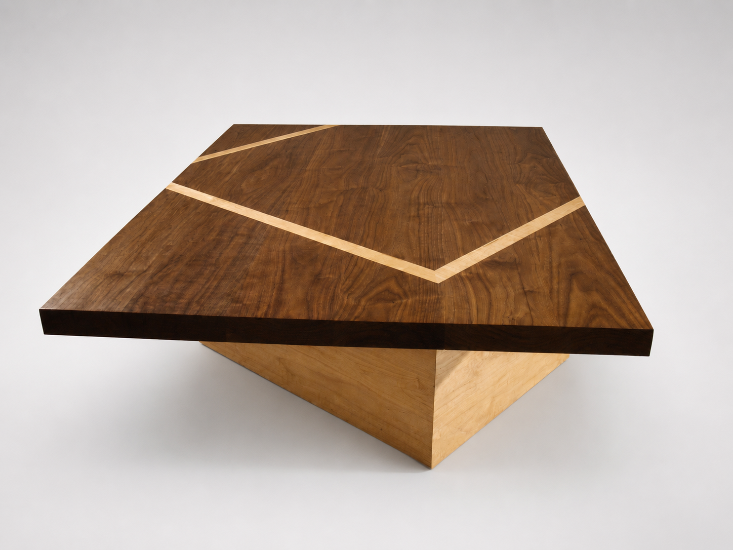 A wooden coffee table with a geometric design, featuring a darker wood top with lighter wood inlays forming a triangular pattern.