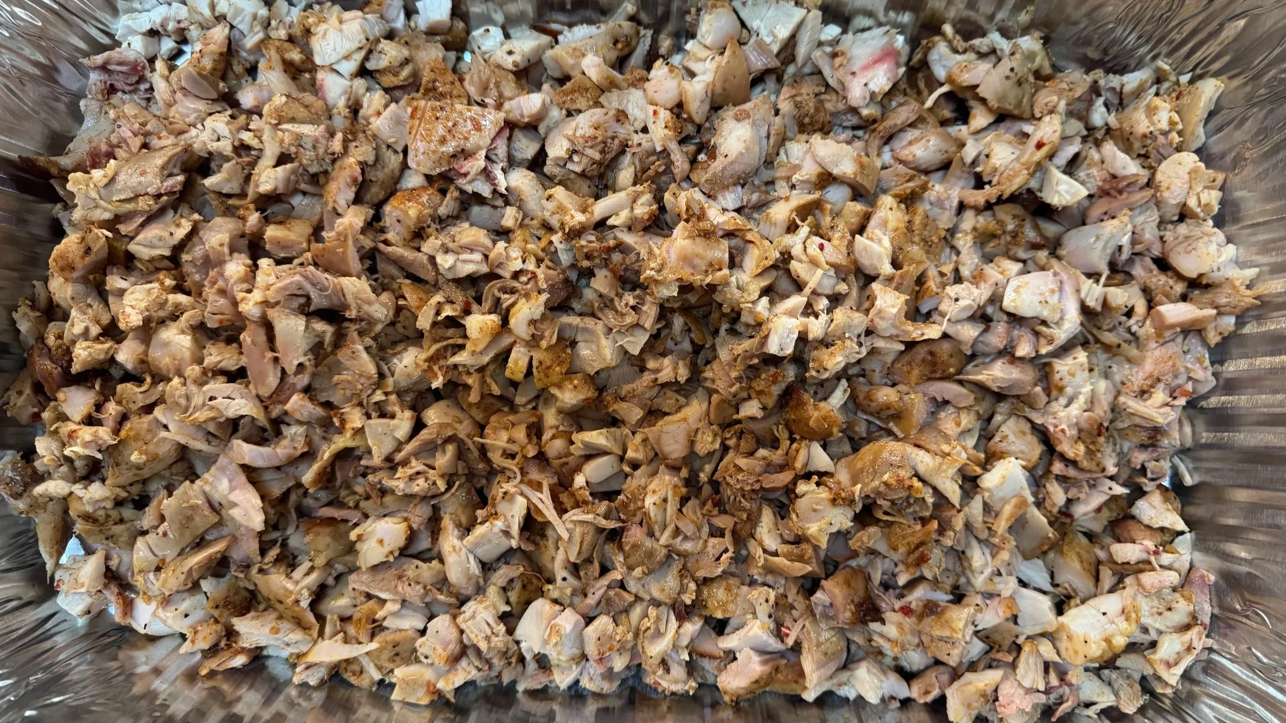 Cooked, chopped chicken pieces in a metal tray.