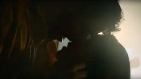 Silhouetted couple kissing in a dimly lit setting.