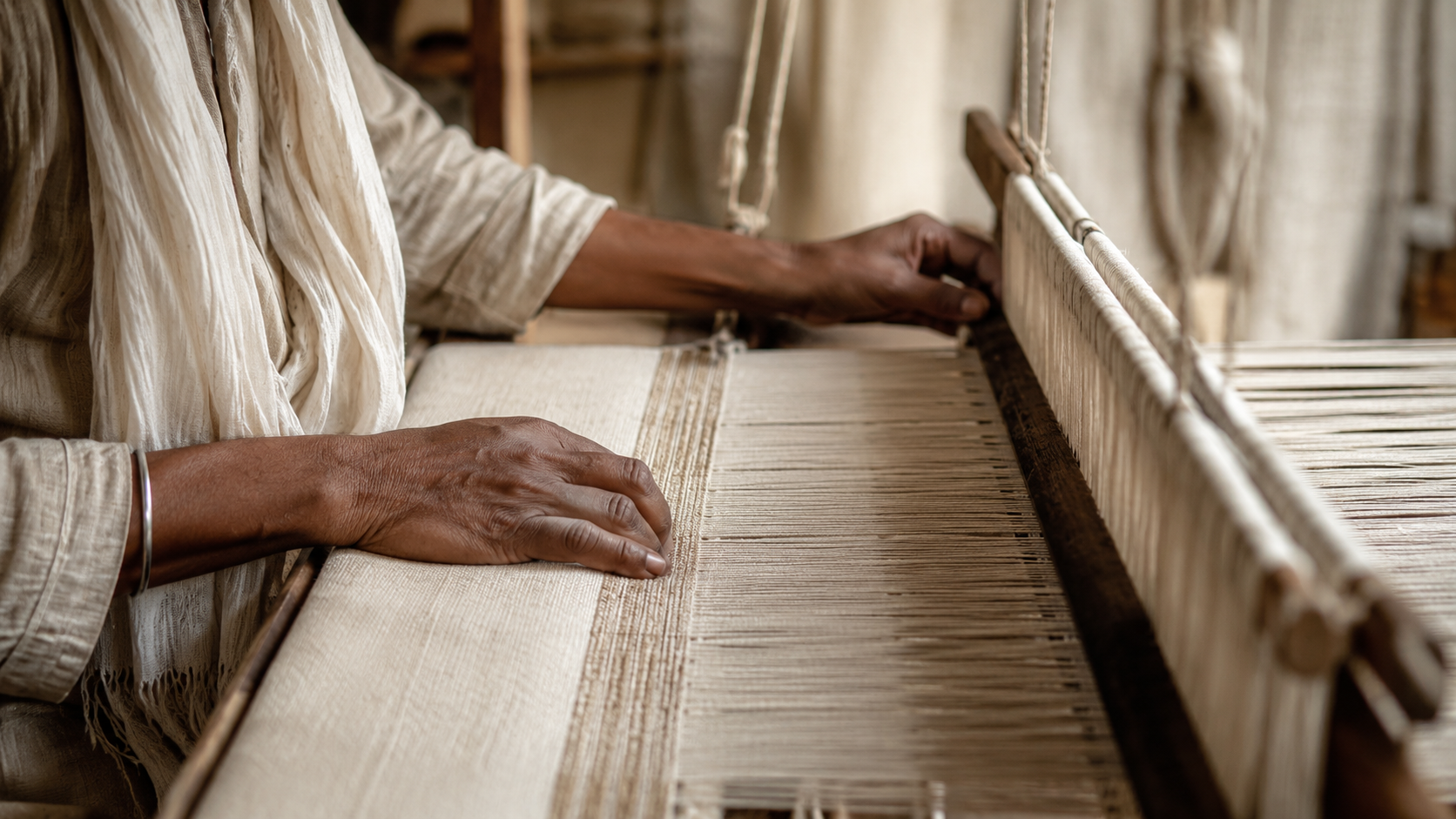 Close-up of a person weaving fabric on a traditional loom, focusing on hands and loom parts.