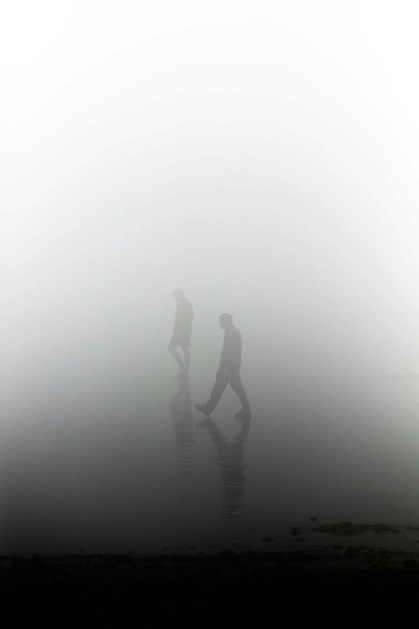 Twee afgevlakte silhouetten wandelen langs een mistige rivier met stille waterreflecties, wat een gevoel van algehele hopeloosheid uitstraalt.