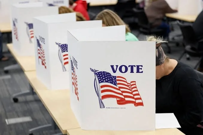 Voting booths with American flags on a table at a polling station.