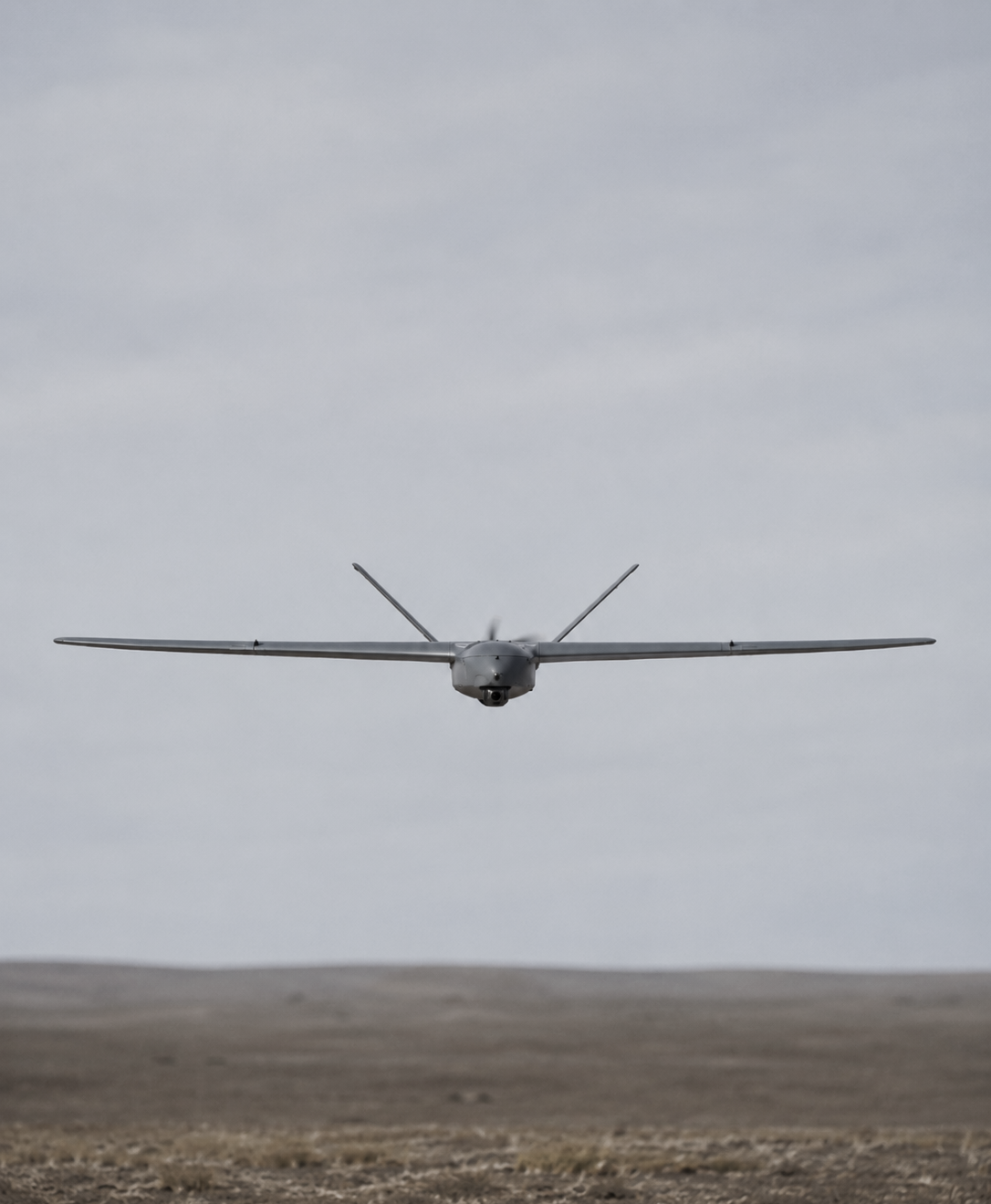 A drone flying in the sky over a barren landscape.