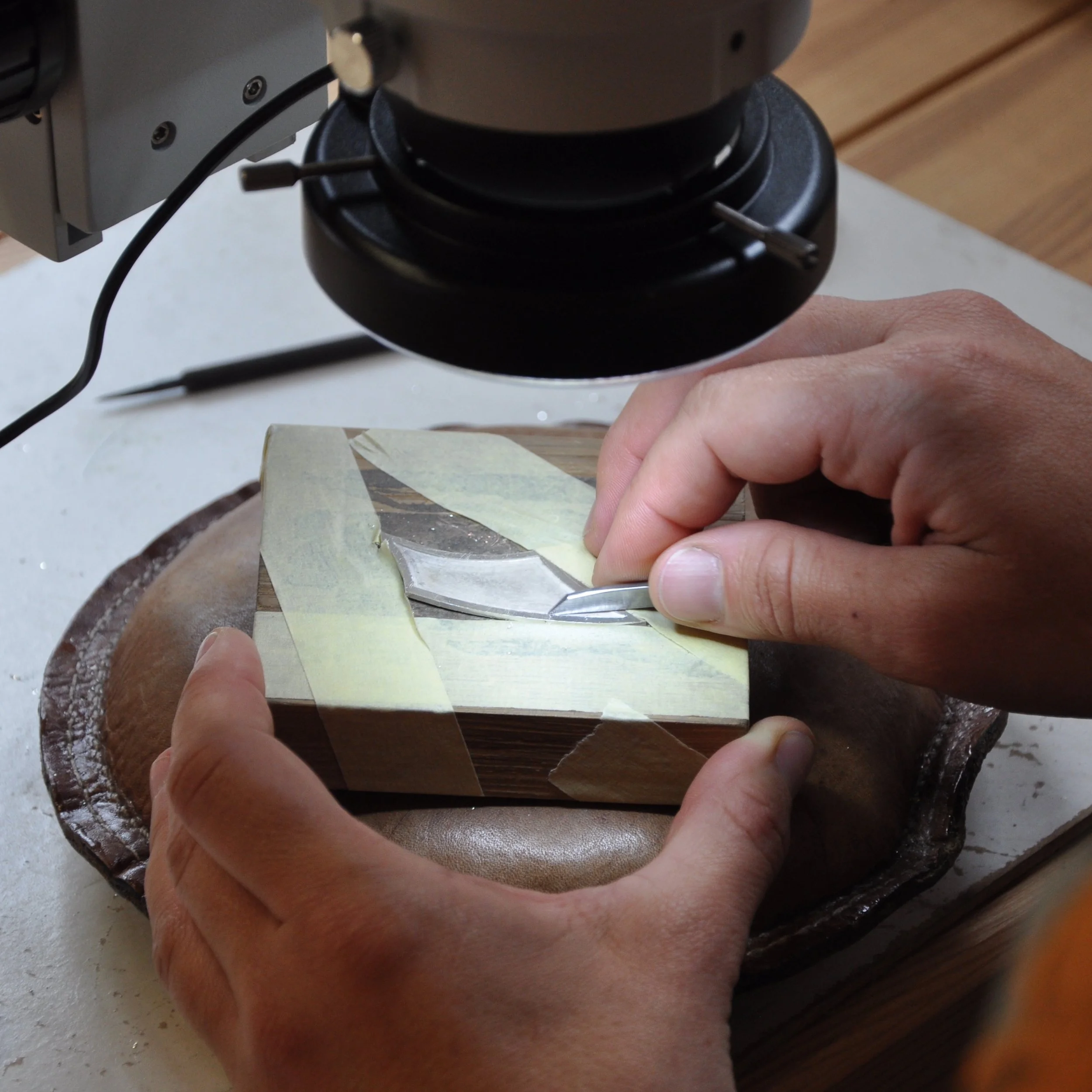 Close-up of a person engraving silver using a microscope