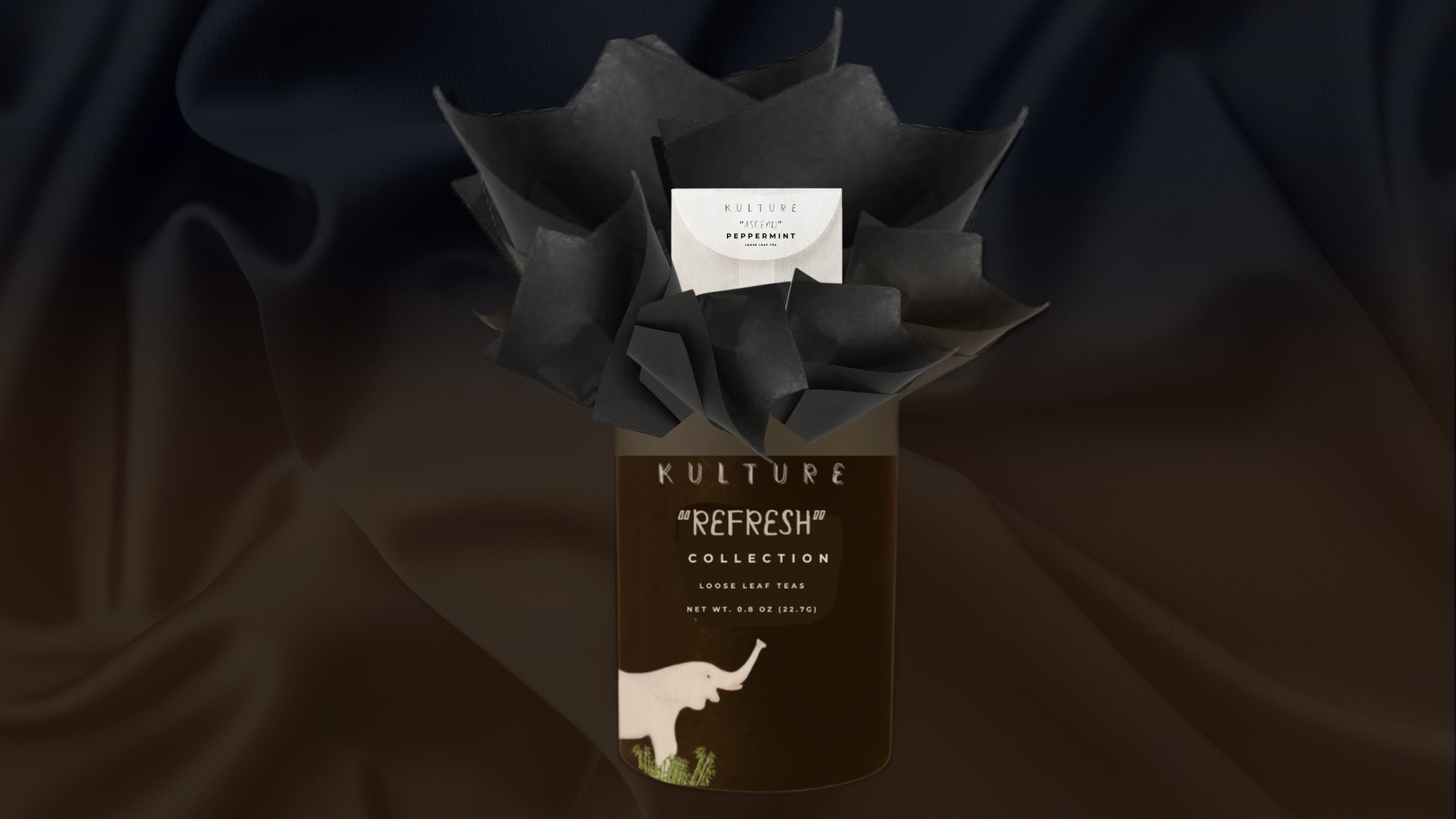 A tea package labeled 'Kulture Refresh Collection' with a black bow wrap. The package has an elephant graphic and states 'loose leaf teas' and 'net wt. 0.8 oz (22.7 g).'