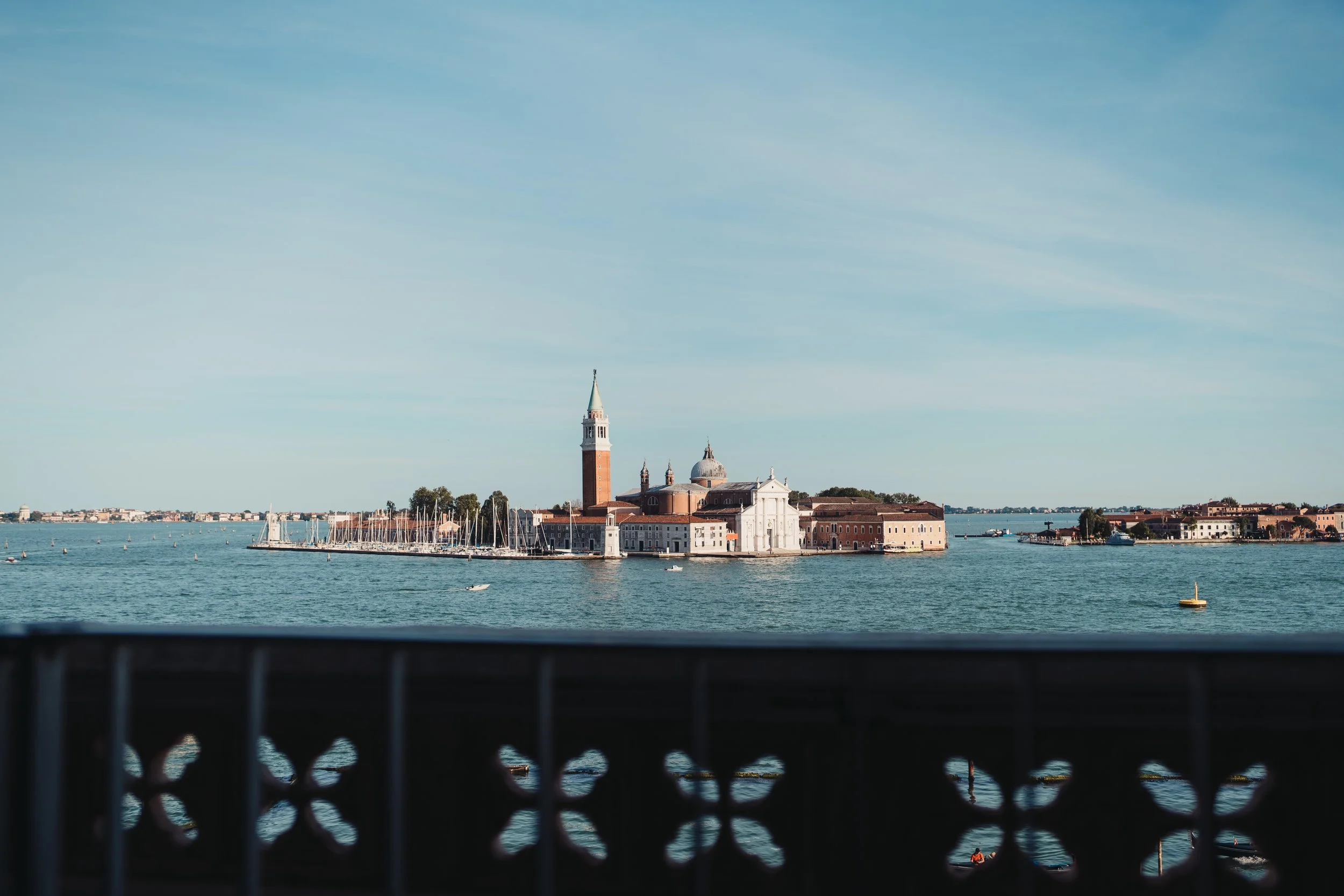 Vue sur une ville italienne avec un bâtiment à clocher et une grande coupole, vue depuis un pont au bord de l'eau.