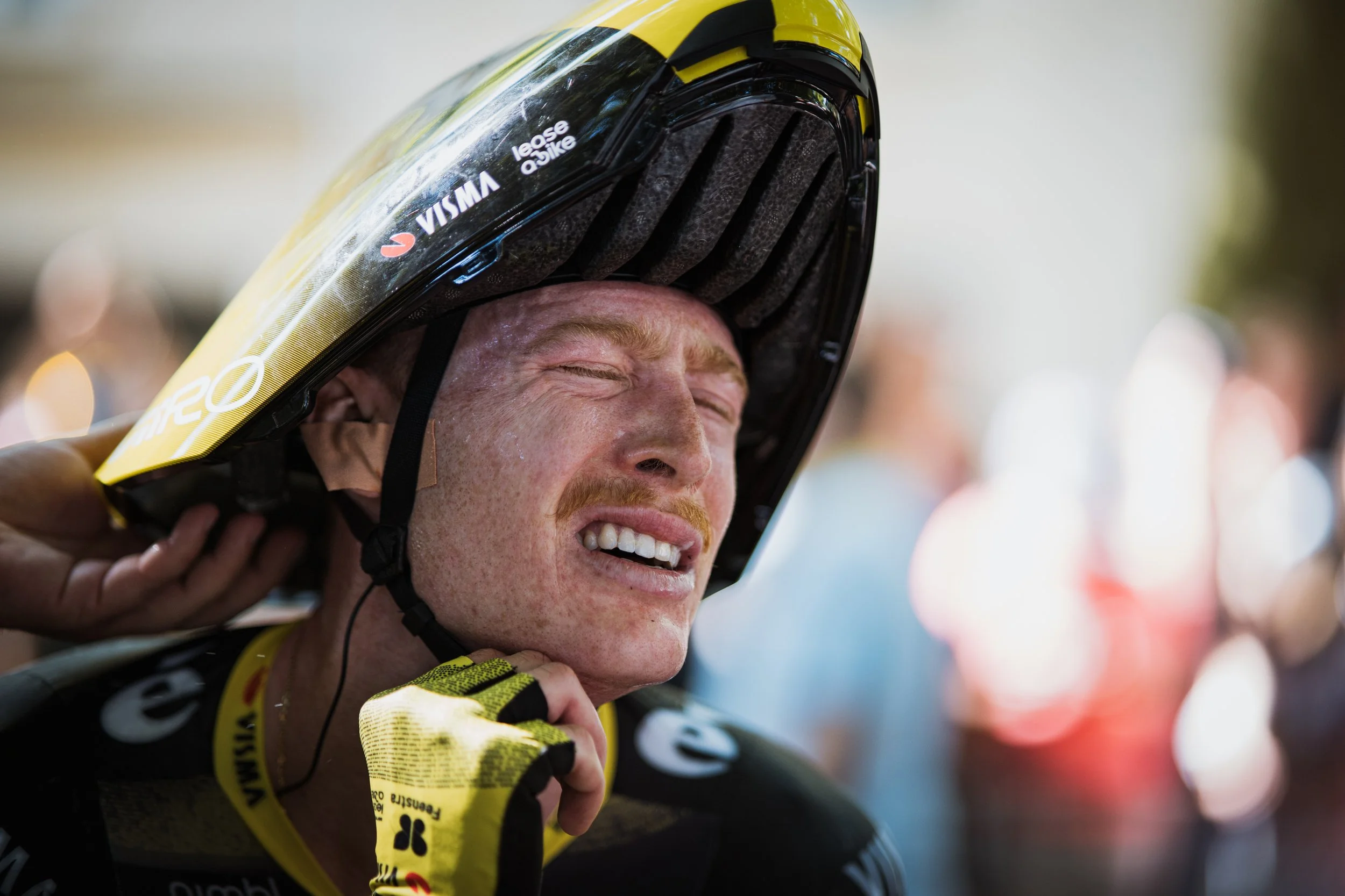 Un homme souriant, portant un casque de moto, en tenue de cyclisme, semble heureux ou excité.