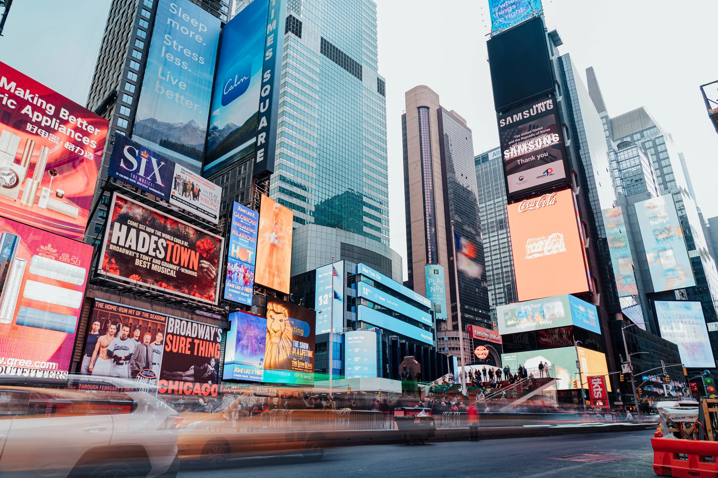 Une scène urbaine de Times Square à New York avec des écrans publicitaires colorés et des gratte-ciel modernes.