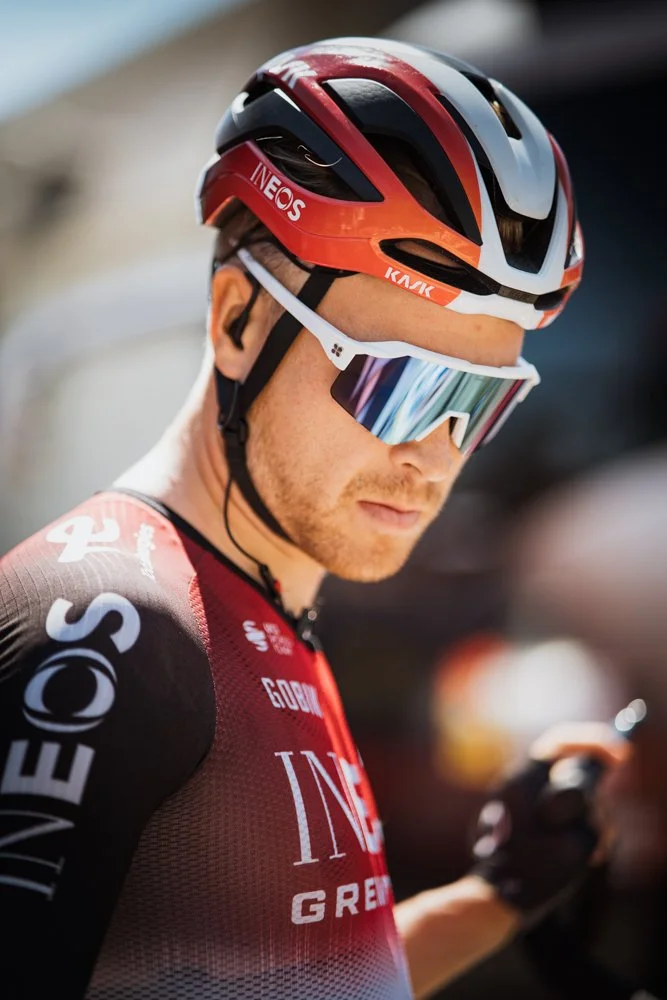 Cycliste portant un casque rouge, des lunettes de soleil miroir, un maillot rouge et noir, et tenant un téléphone