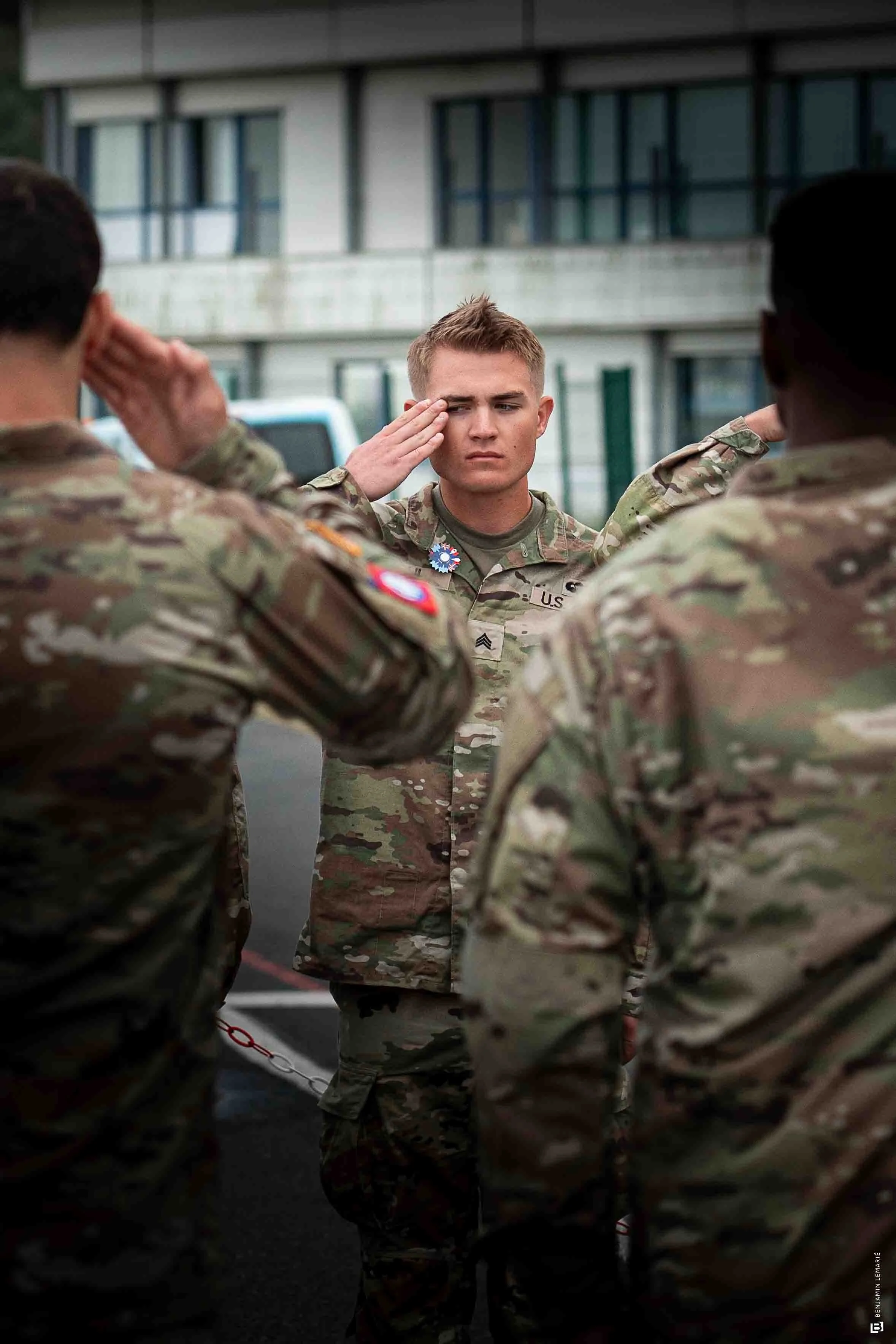 Une jeune femme soldat en uniforme militaire saluant lors d'une cérémonie militaire extérieure.