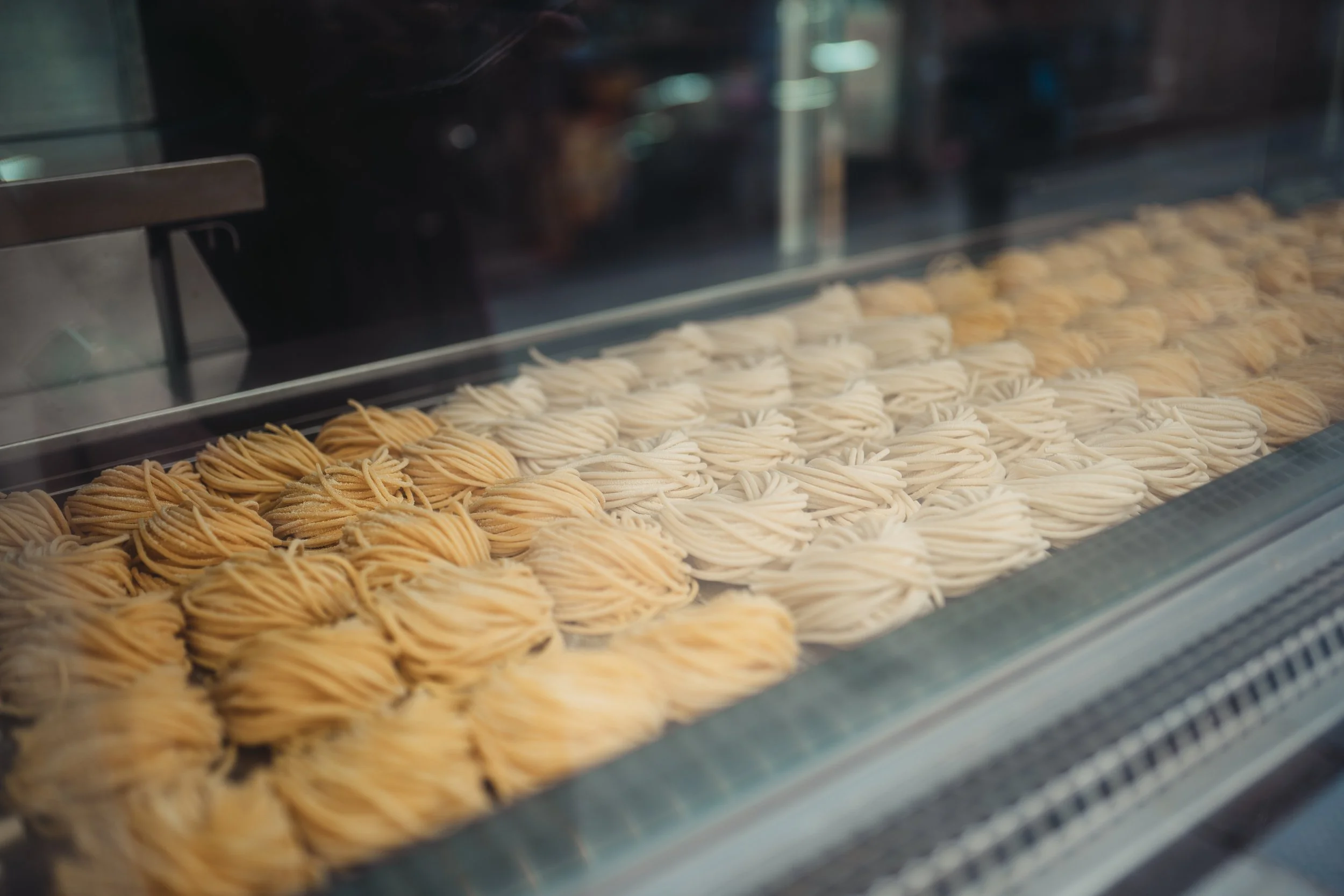 Display de pâtes fraîches en filaments dans une vitrine de pâtisserie.