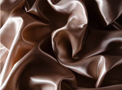 Close-up of crumpled satin fabric in shades of brown and beige.