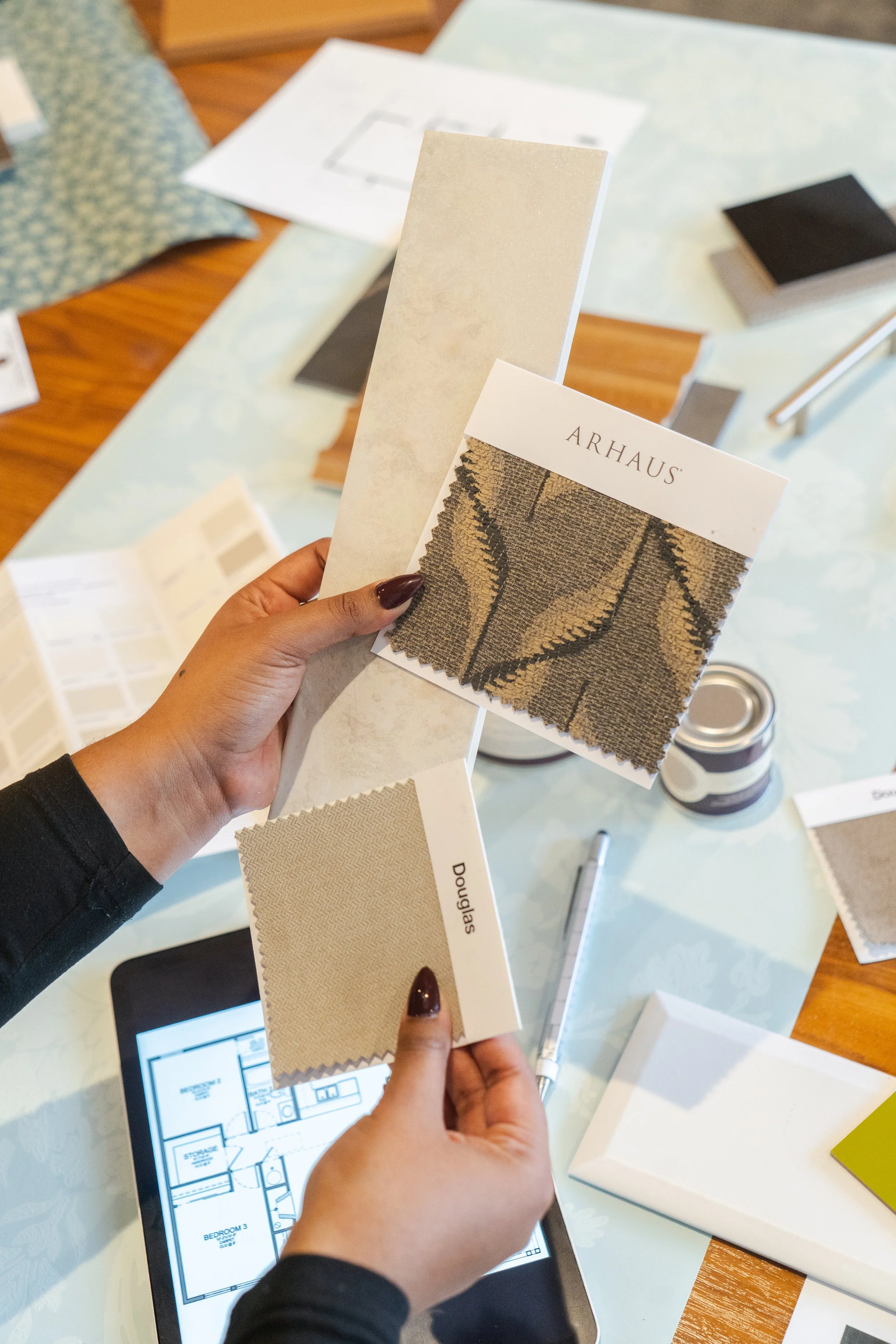 Person looking at various marble and stone sample tiles on a table.