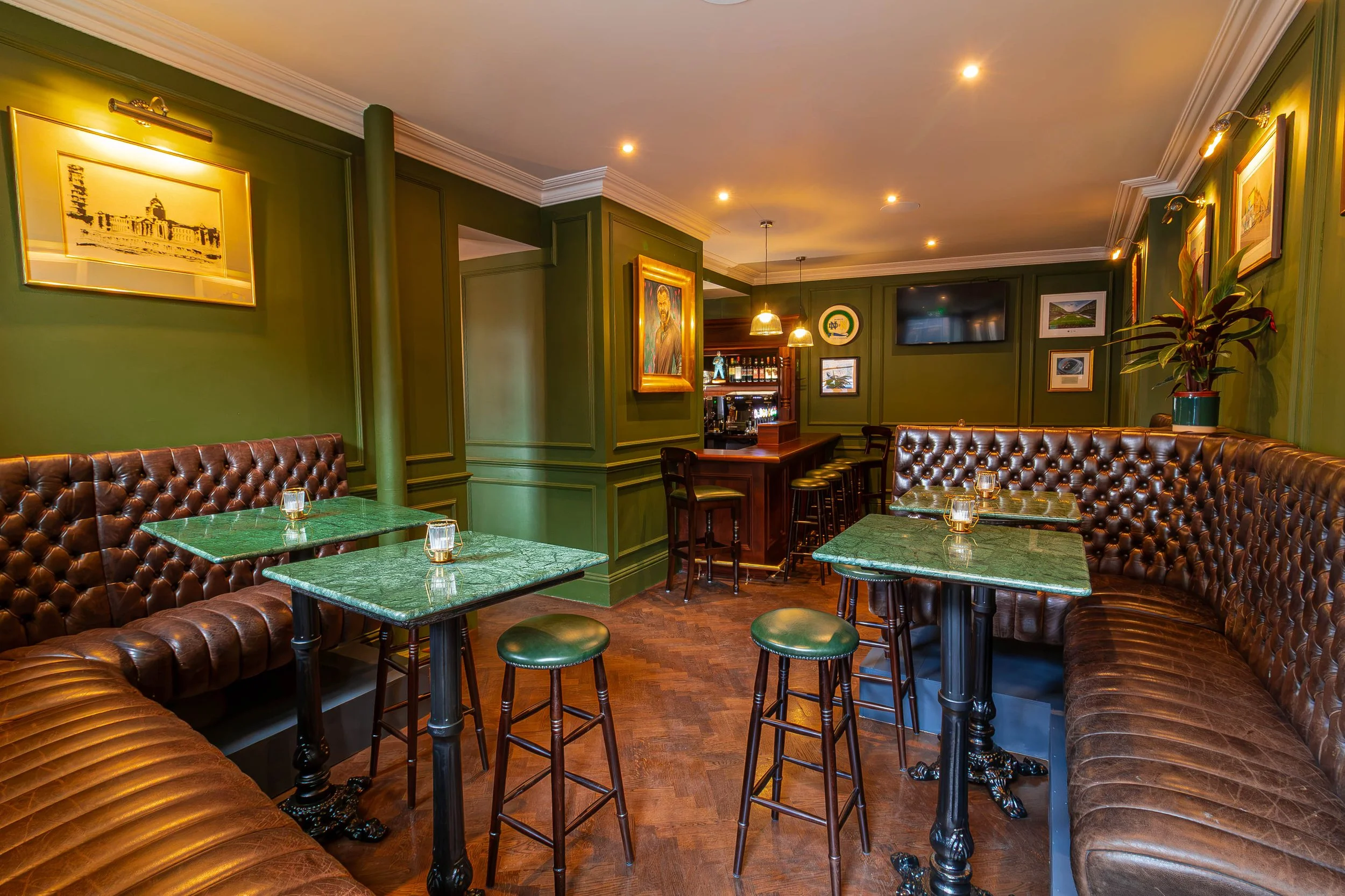 Pub and tables section in The Snug. Green marble tables, brown leather couches