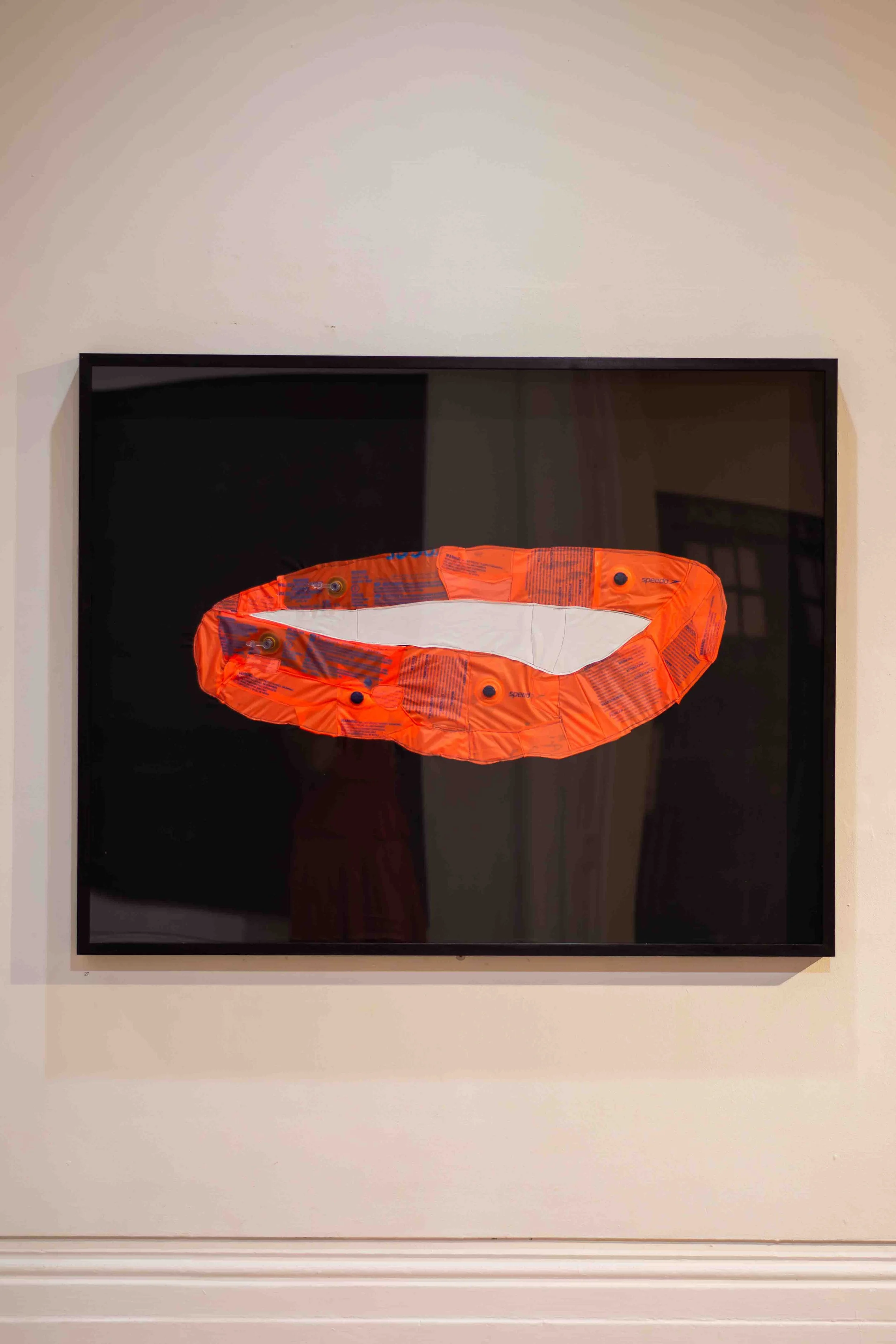 Artwork depicting an orange lifebuoy with white accents and black details, mounted on a black background.