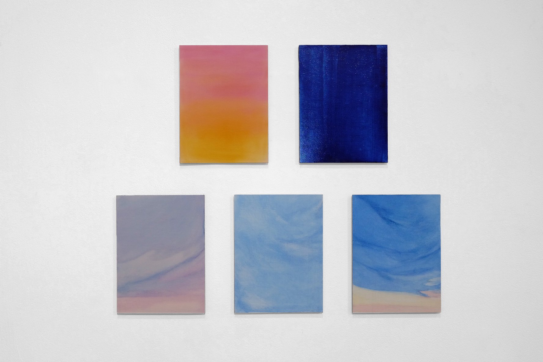 A wall display with six rectangular abstract paintings arranged in two rows of three, featuring various shades of pink, yellow, blue, and purple with swirling and gradient patterns.