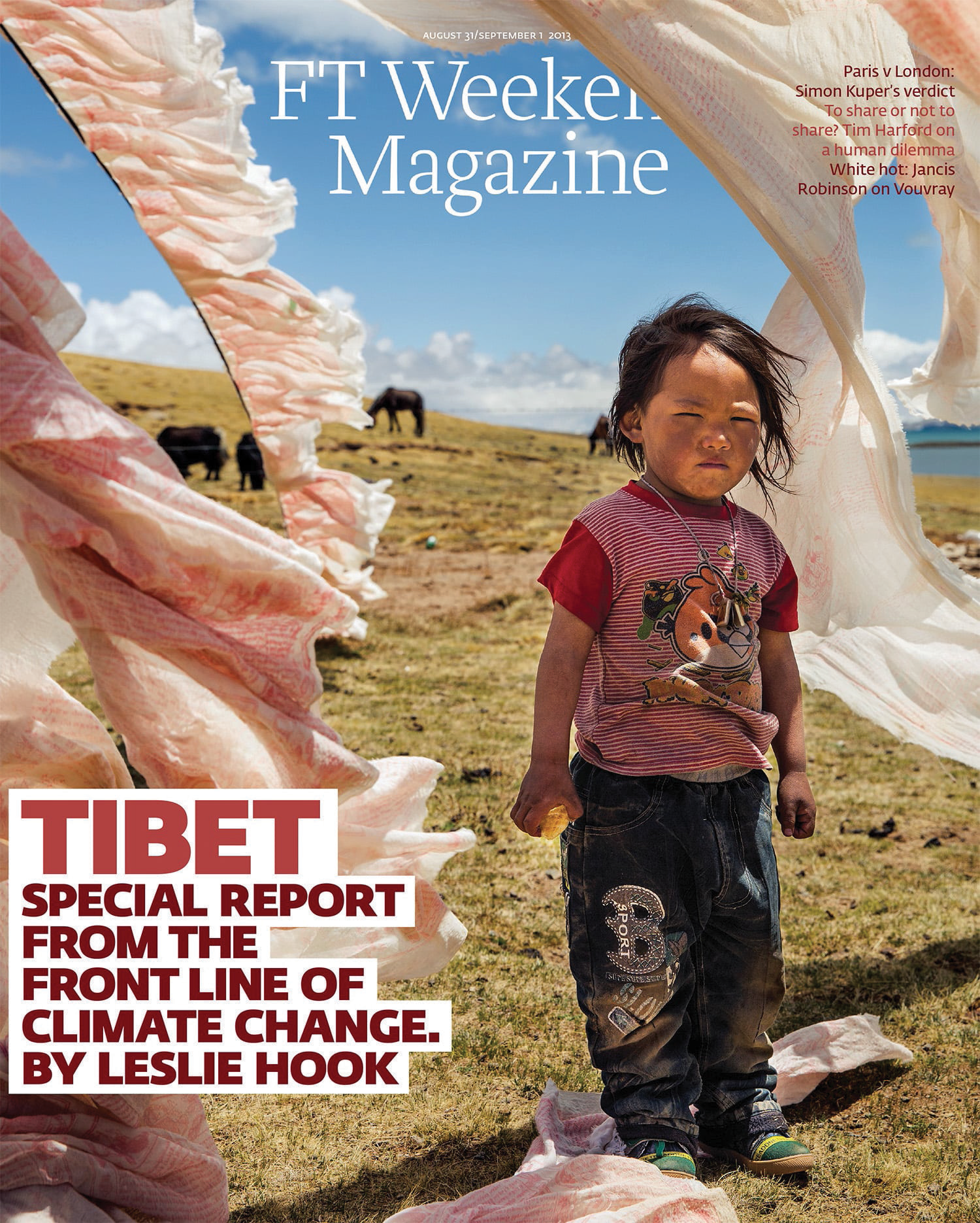 A young child standing outdoors on a grassy plain, surrounded by cloth or fabric hanging in the air. In the background, there are horses grazing, under a blue sky with clouds. The cover features a publication title and headlines about climate change 