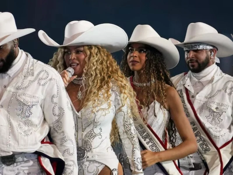 Group of four people dressed in white outfits and large cowboy hats.