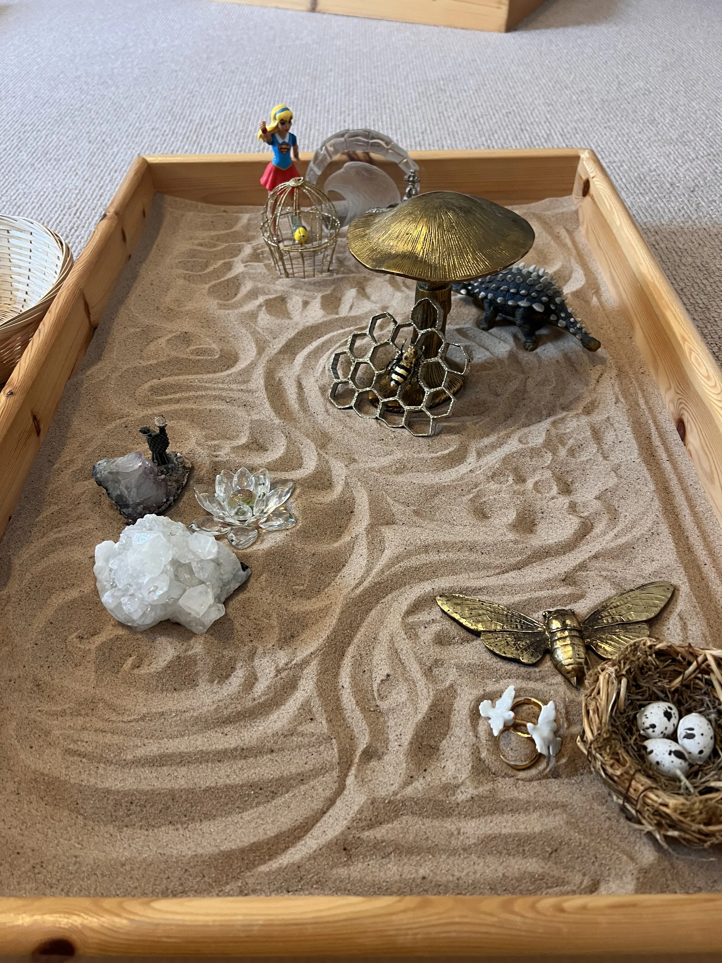 A sandtray with small figures and stones in a calm counselling room