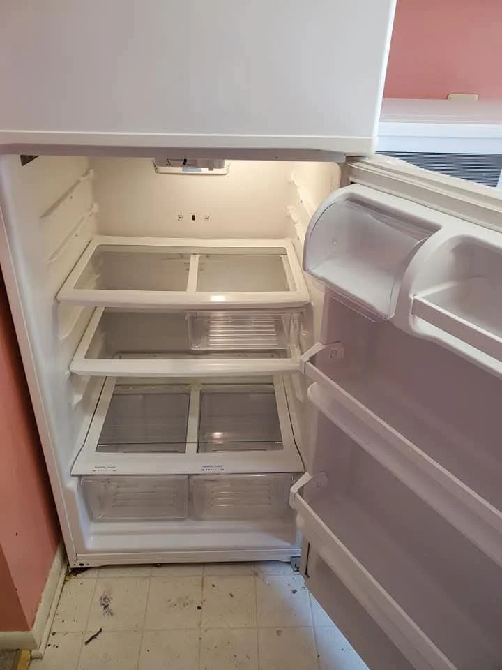 Empty white refrigerator with glass shelves and door compartments, open door revealing interior.