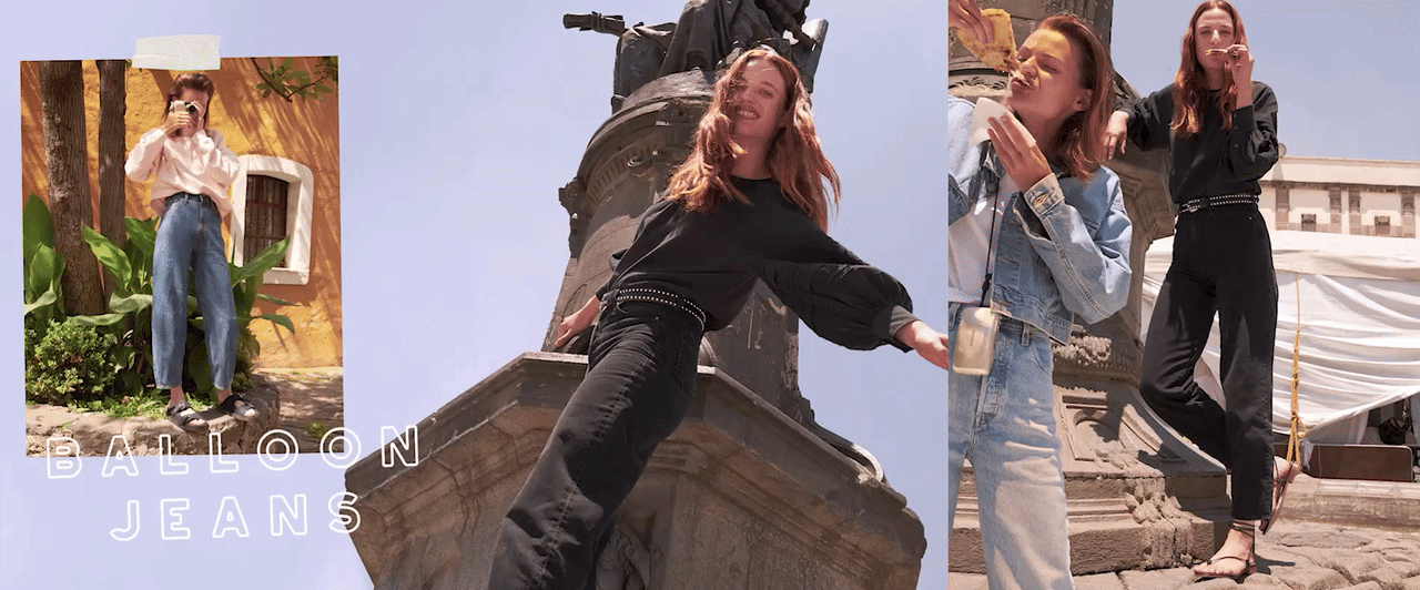 Three women in jeans and casual tops posing outdoors in front of historical architecture, with blue sky background.