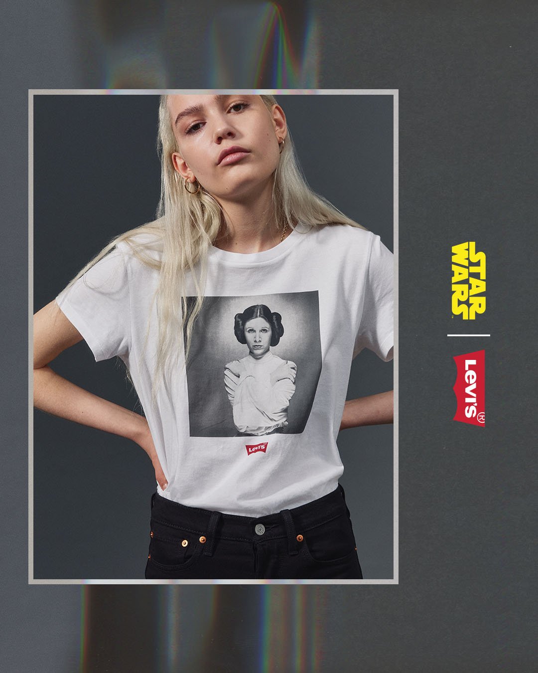 Young woman with long blond hair wearing a white T-shirt with a black and white photo of Princess Leia from Star Wars and Levi's logo, standing against a dark background.