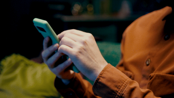 Person holding and using a smartphone in an indoor setting.