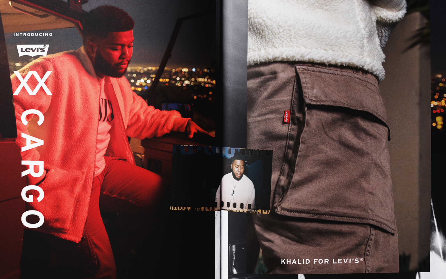 A man dressed in a beige fuzzy jacket and brown pants standing on a balcony at night overlooking a city, with a poster of another man wearing a white jacket in front of him and a cityscape in the background.