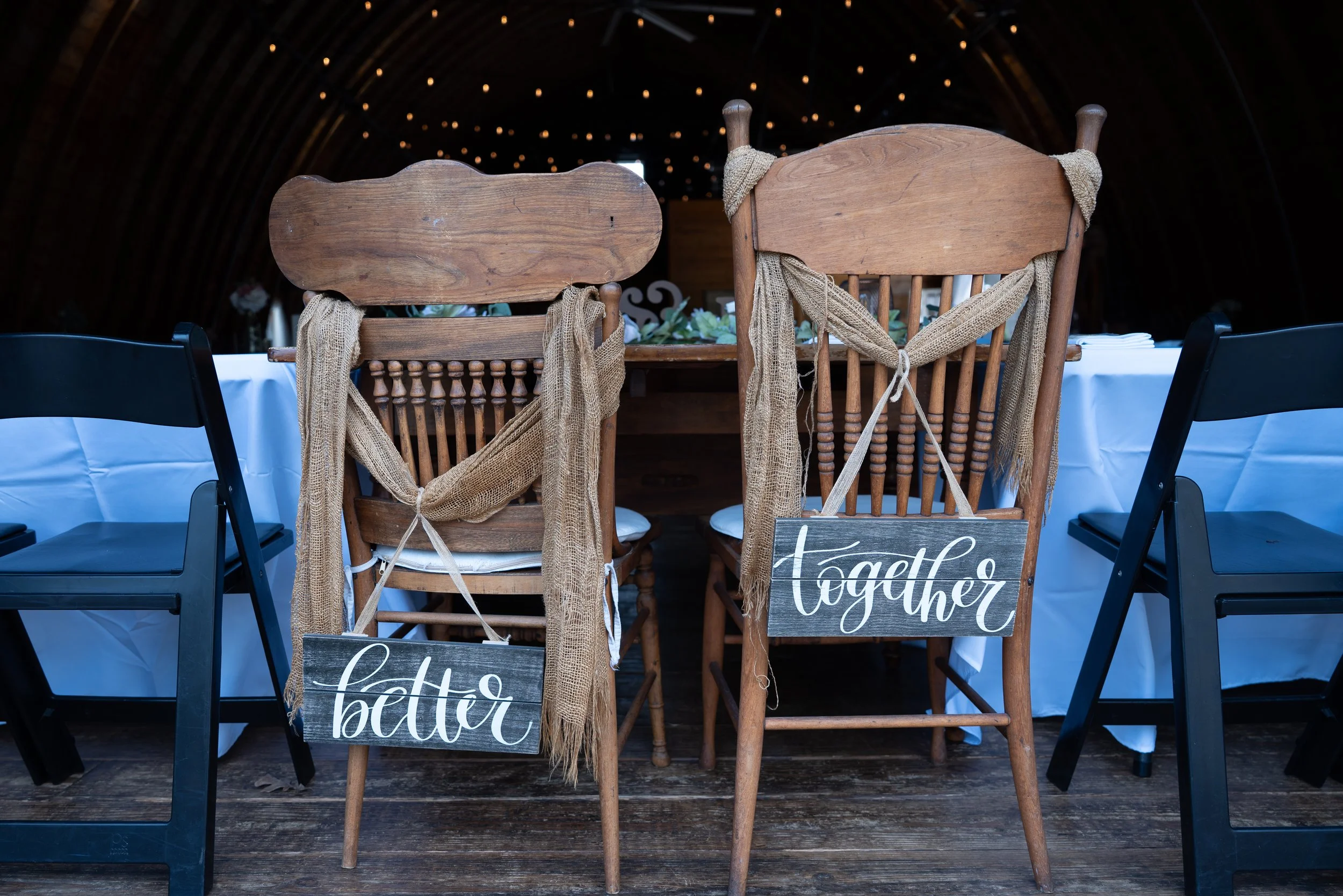 Two wooden chairs with burlap decorations and
