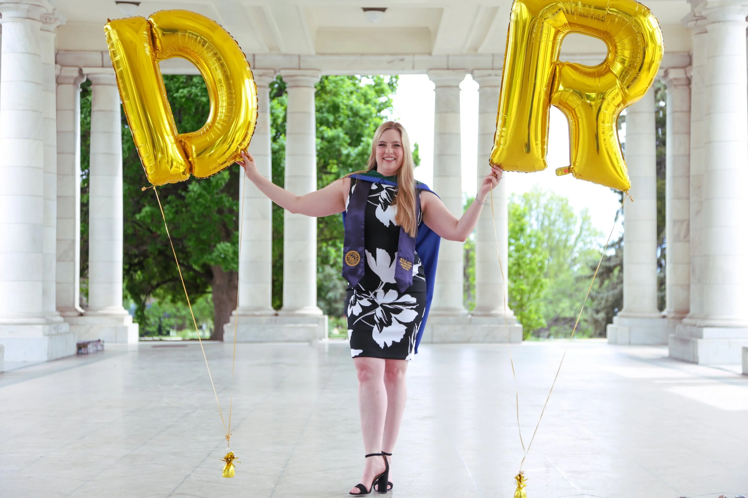 A recent med school grad holds us "dr" shaped balloons in the grand colonnade. The white marble is a very classic look for portraits in Colorado.