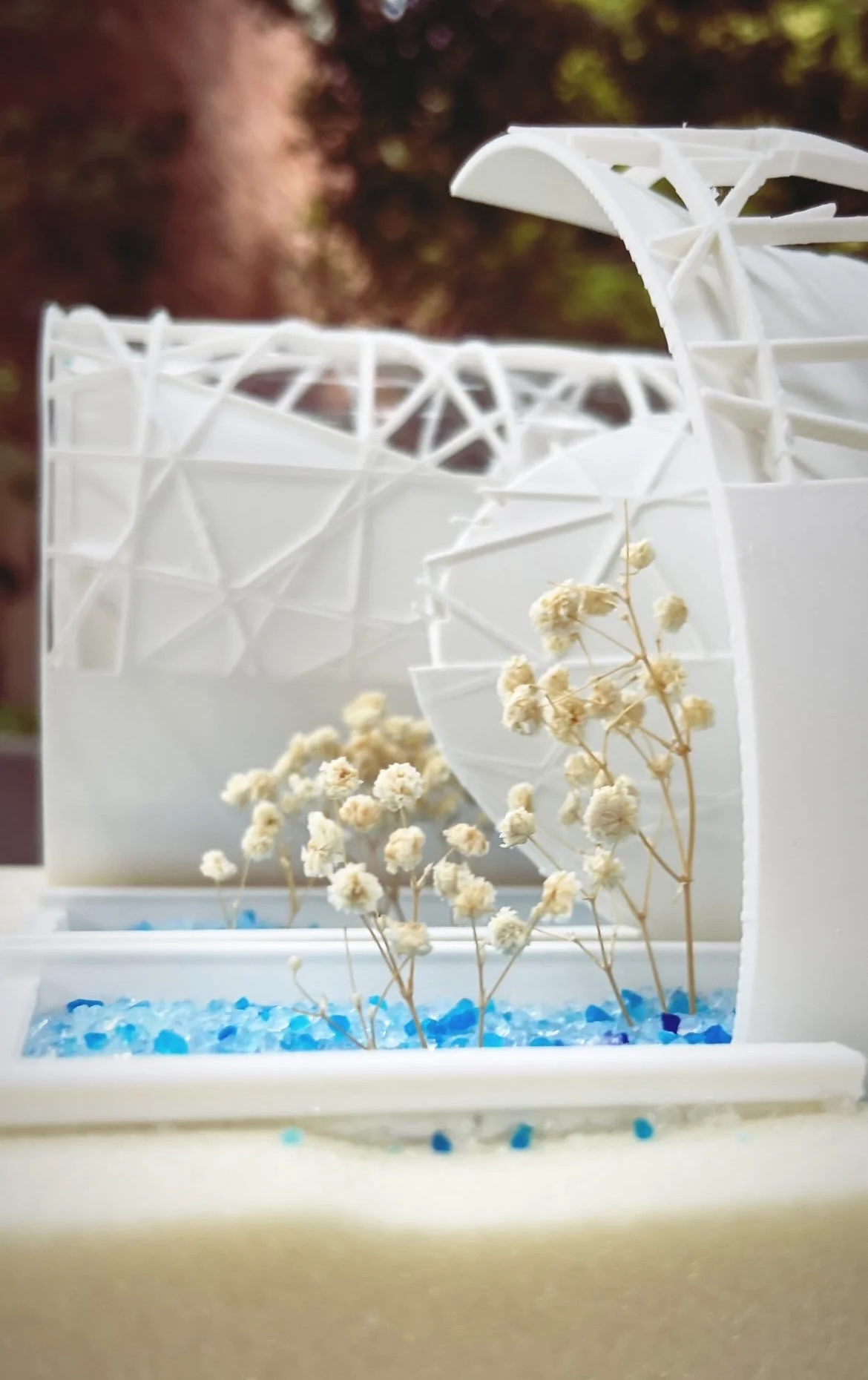 Architectural exposed structure model with trees and blue stones.