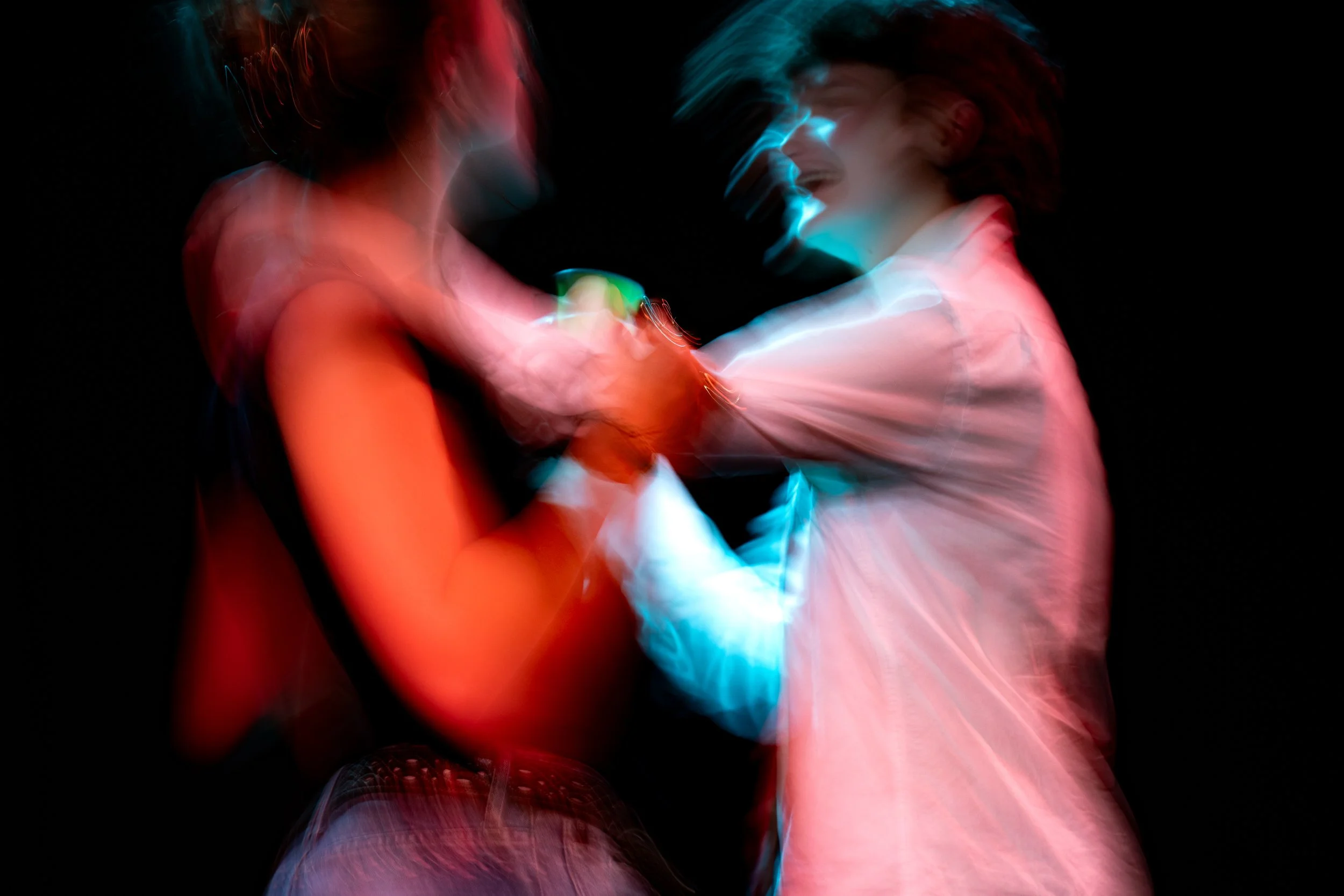 Two people embracing and smiling, with colorful light effects creating a blurred, abstract appearance.