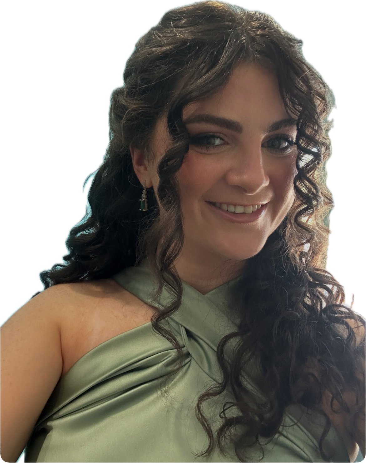 A woman with long, curly brown hair smiling, wearing a light green, one-shoulder dress and dangling earrings.