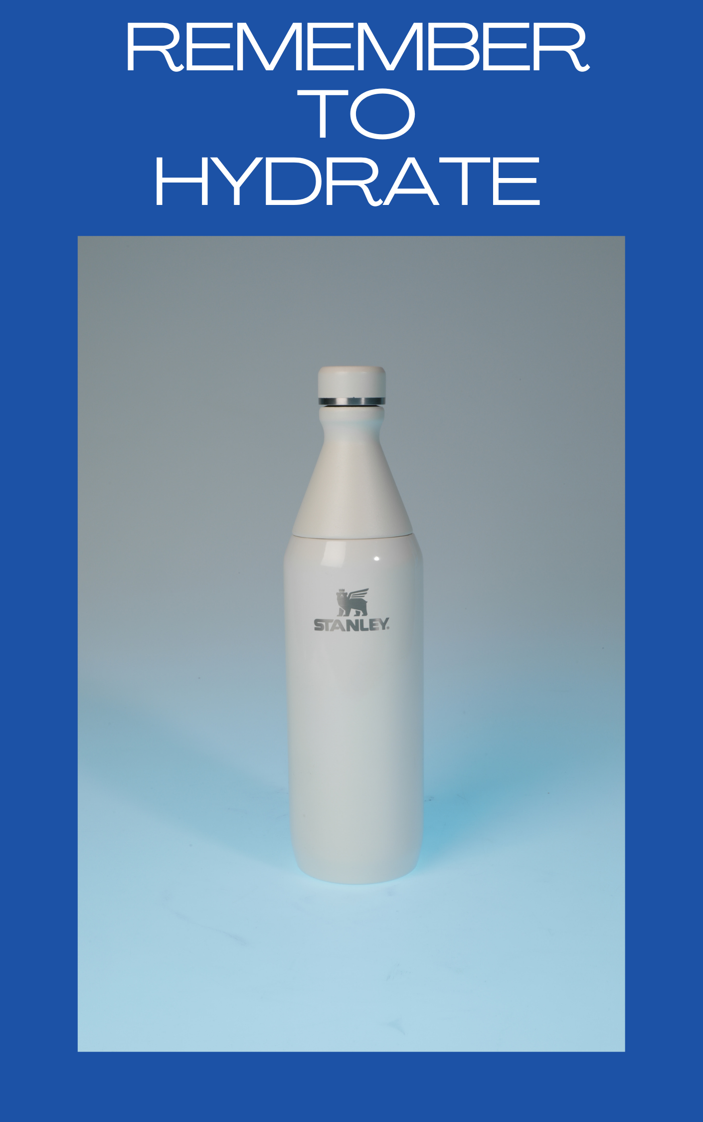 A white Stanley water bottle with a silver band near the top, standing upright against a light blue background, with a dark blue border and a reminder to stay hydrated written at the top.