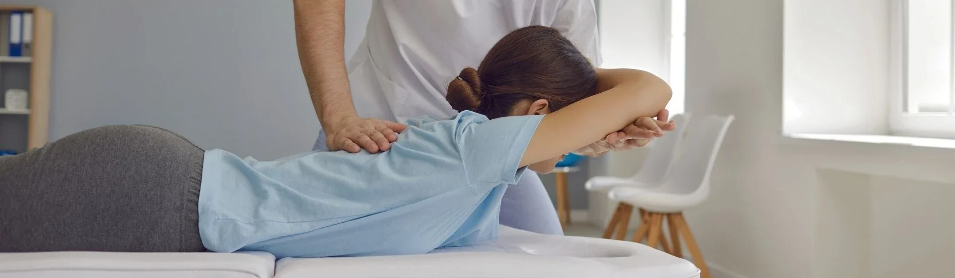 Un infermiere sta praticando la rianimazione cardiopolmonare su una donna adulta sdraiata su un tavolo da esami, in un ambiente clinico luminoso.