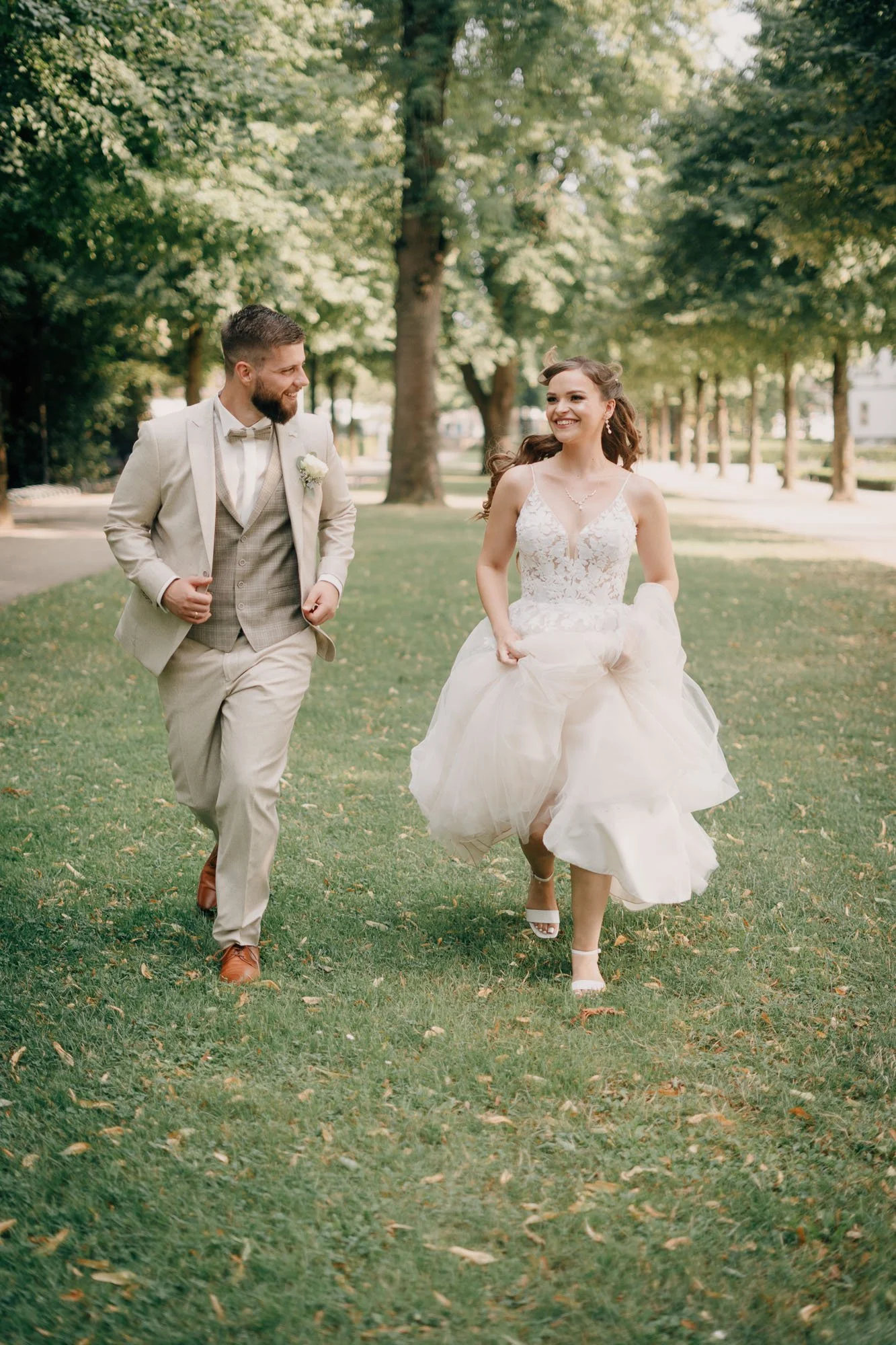 Ein Mann und eine Frau in einem Park, während ihrer Hochzeit, die Frau trägt ein weißes Brautkleid und der Mann einen hellen Anzug.
